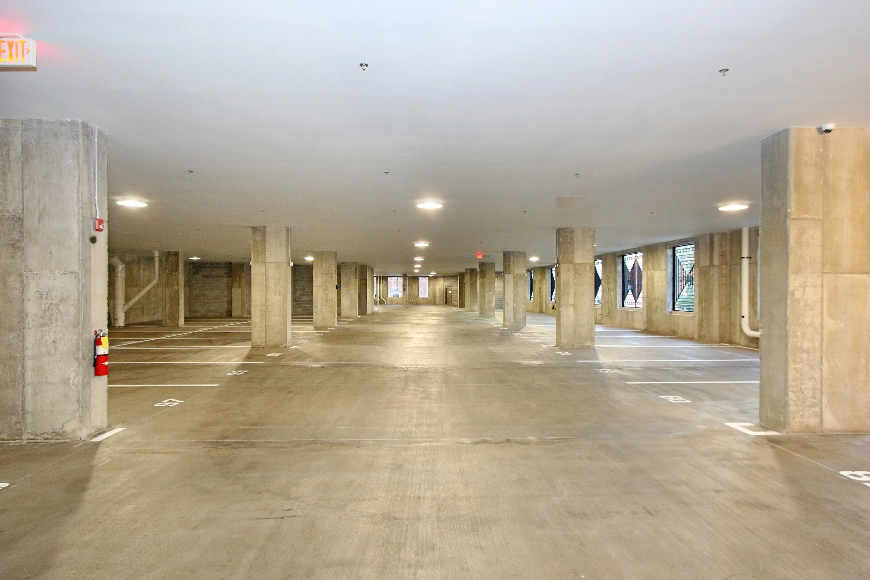 Modern underground parking lot with ample lighting and marked spaces.