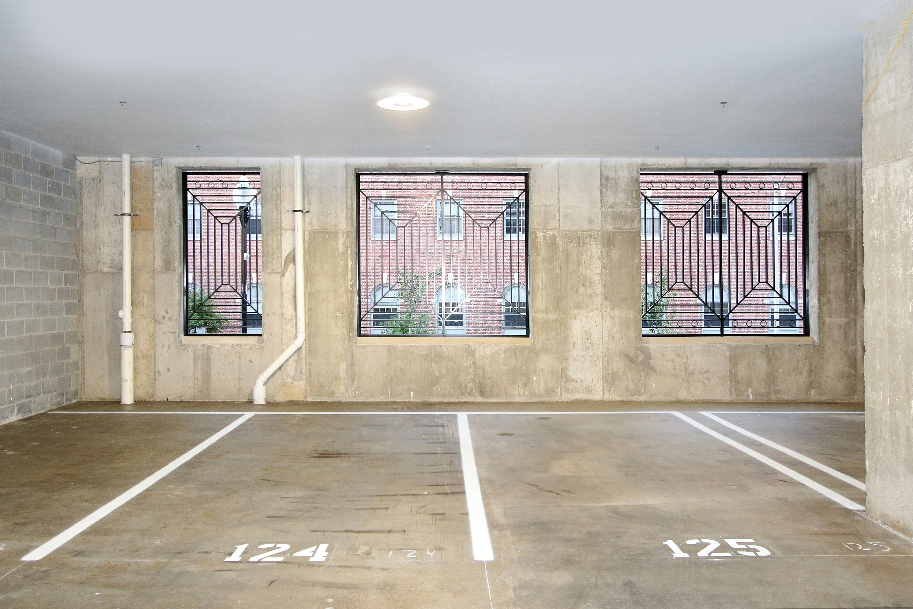 Modern indoor parking area with natural light and secure metal window designs.