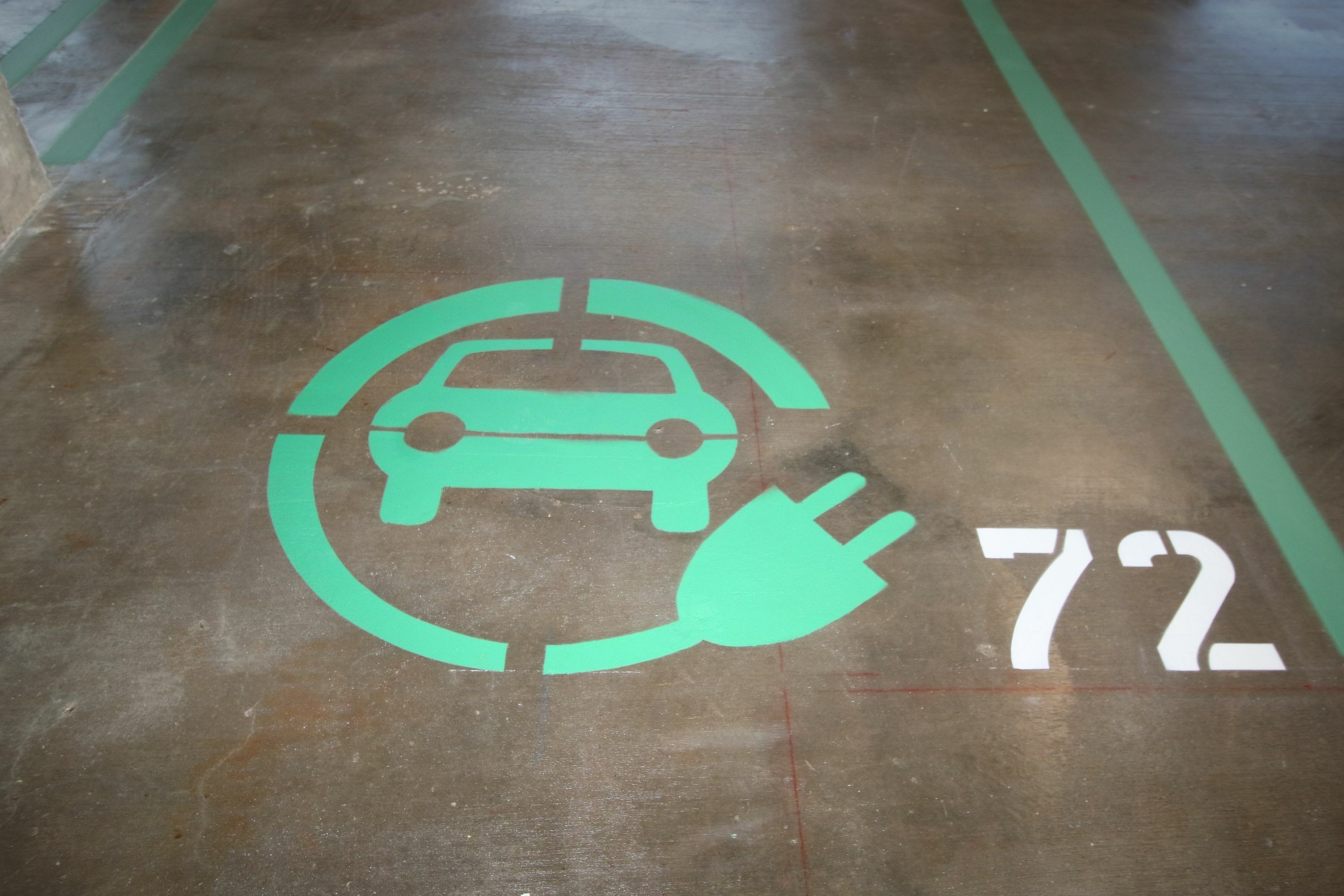 Designated electric vehicle parking spot with green car and plug icon.