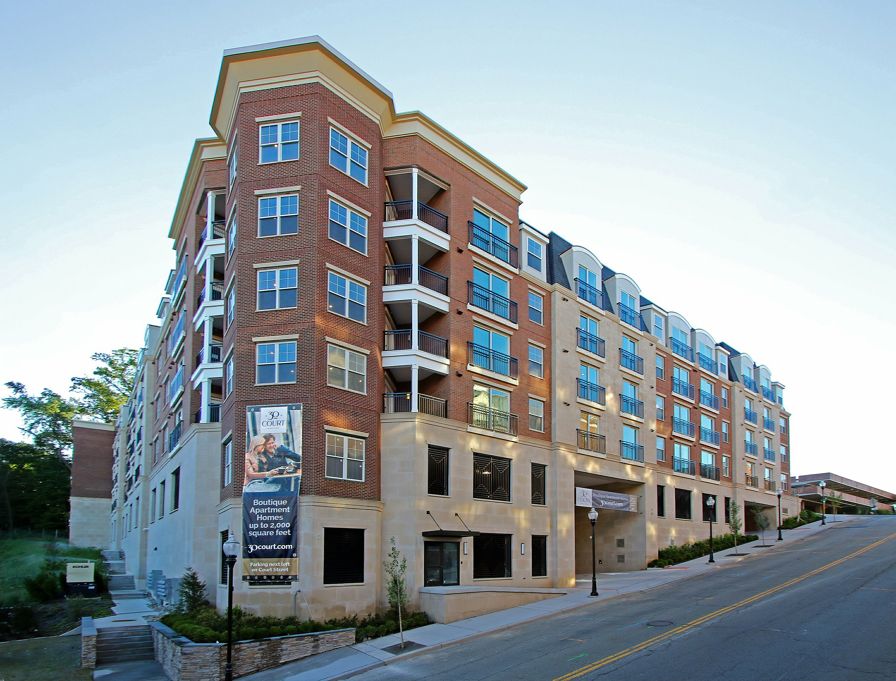 Stunning exterior view of a modern urban apartment building with red brick facade and large windows.