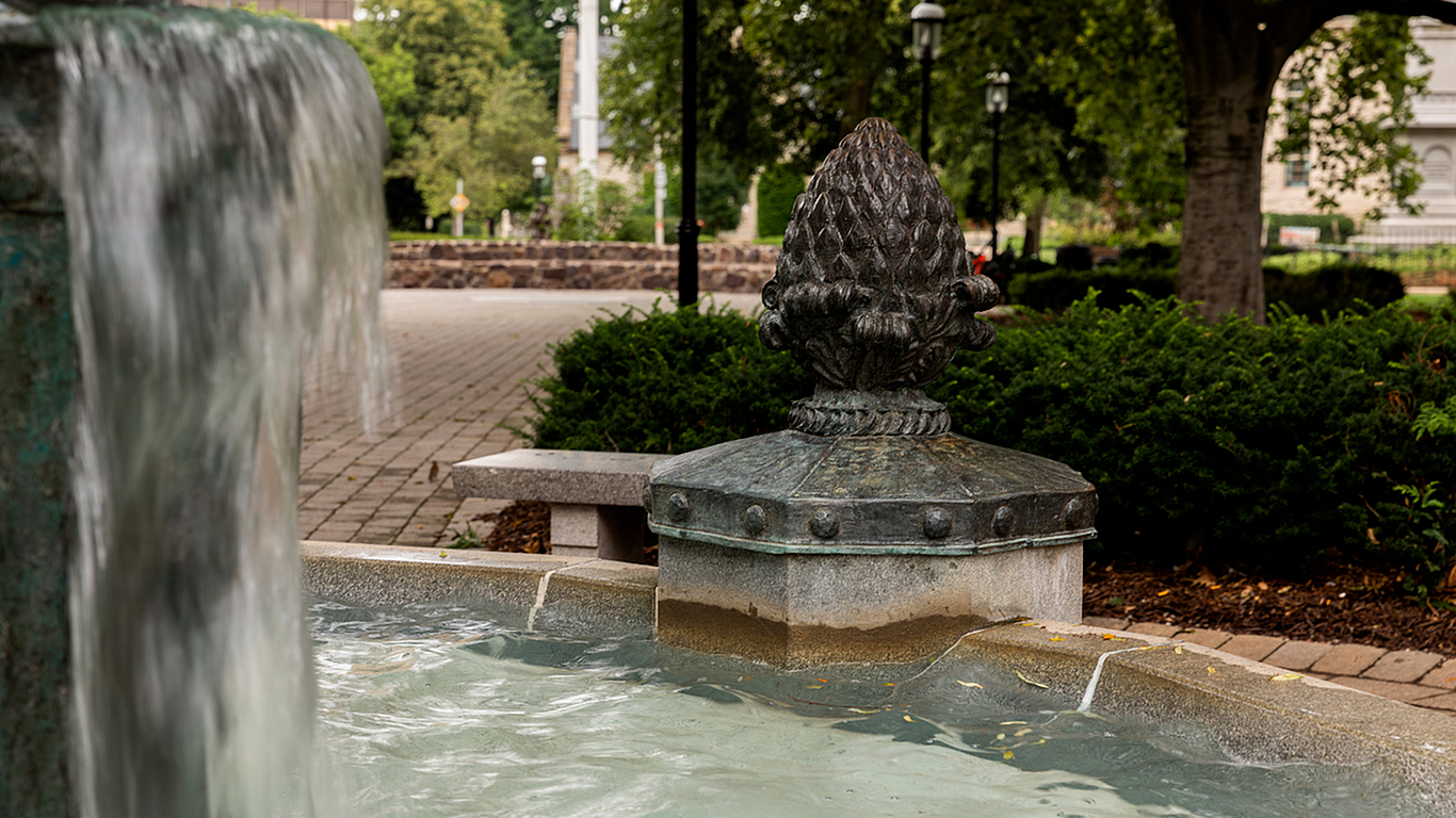 Charming courtyard fountain with cascading water, surrounded by lush greenery and elegant stonework.