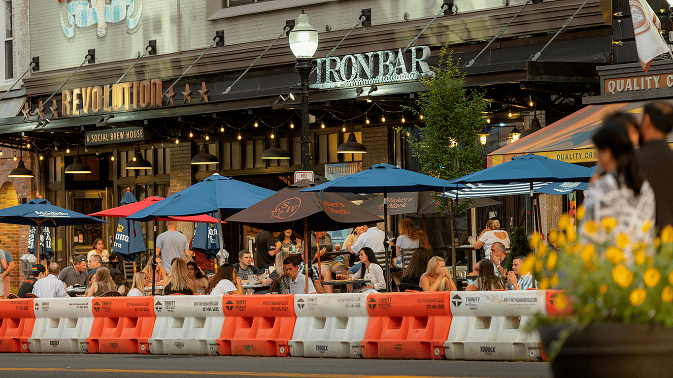 Vibrant outdoor dining scene at Revolution brew house, featuring colorful umbrellas and bustling patrons enjoying an evening out.
