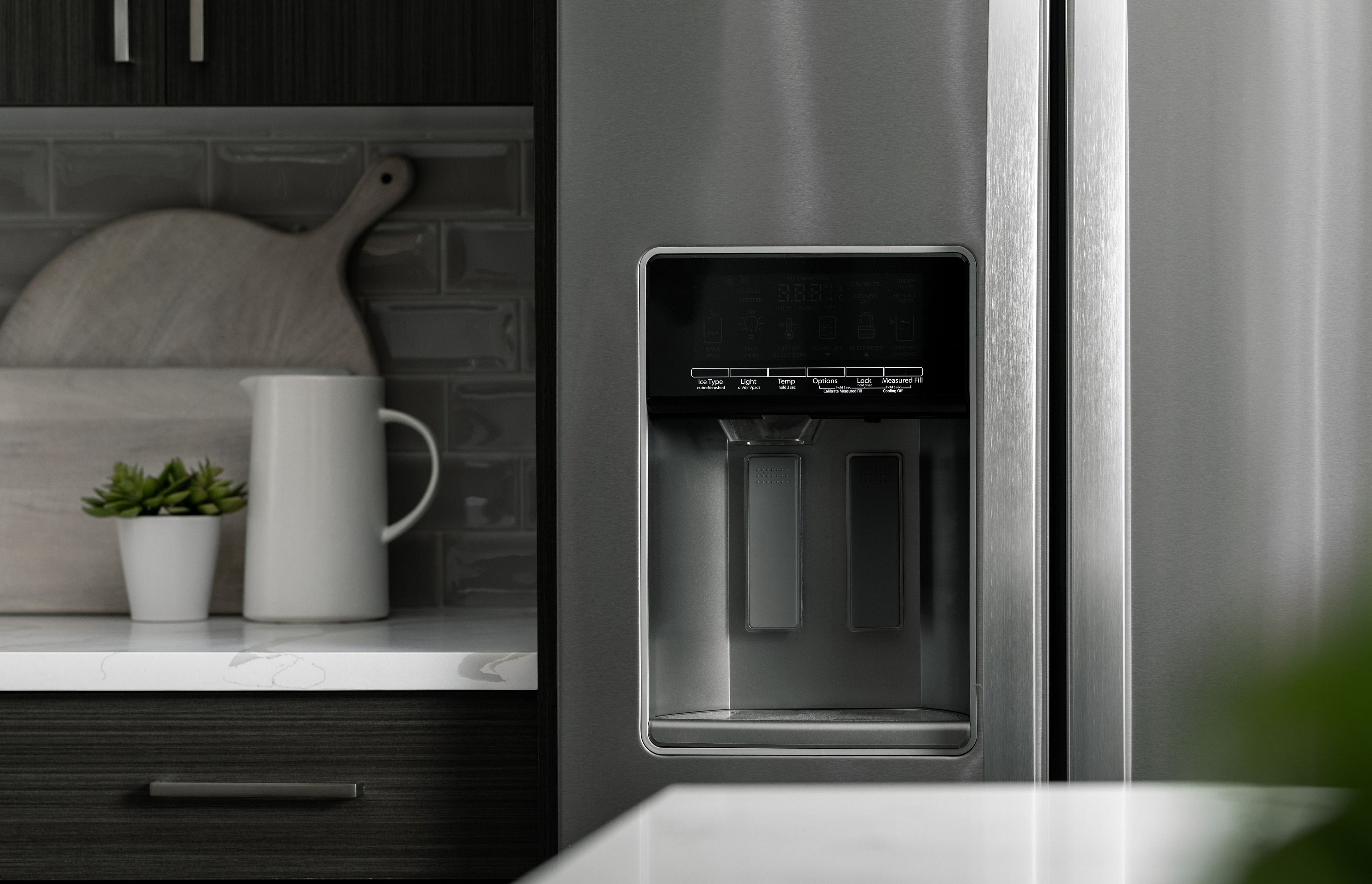 Sleek modern kitchen showcasing stainless steel refrigerator, elegant countertop, and stylish backsplash with minimalist decor.