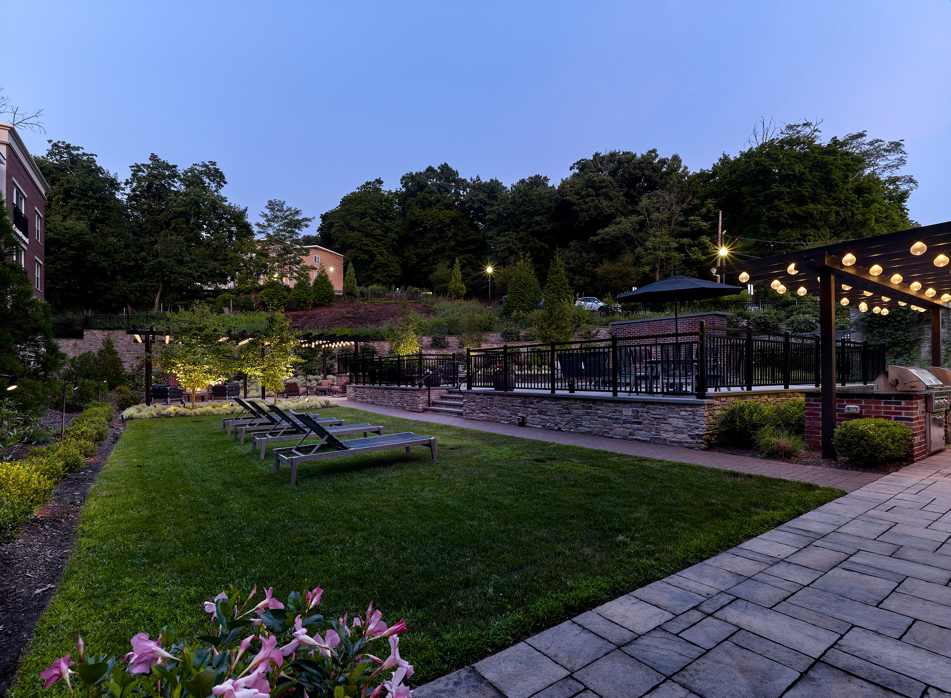 Charming outdoor area with lush greenery, inviting patio seating, and cozy string lights, ideal for relaxing evenings.