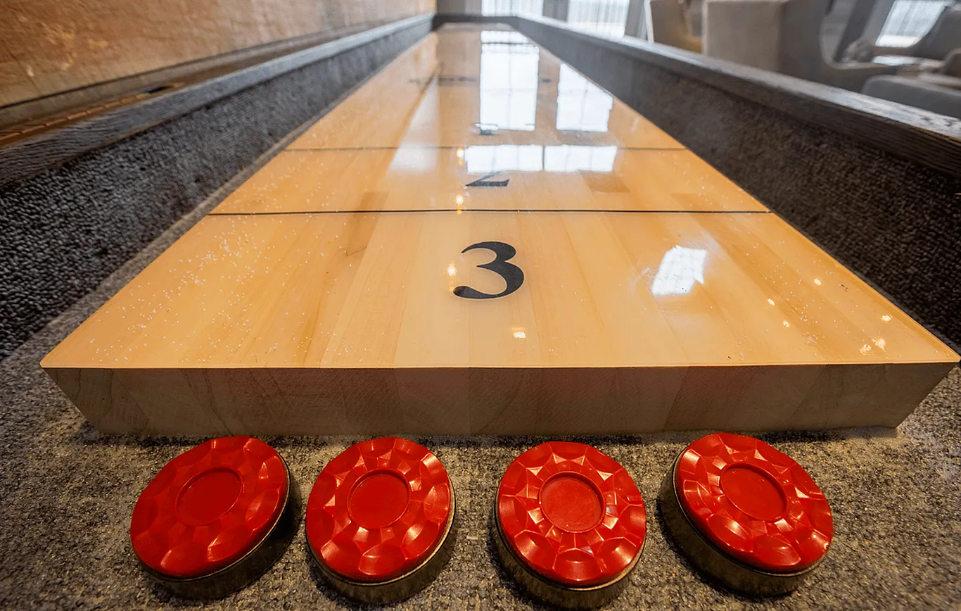 Inviting shuffleboard table with vivid red pucks, ideal for entertaining and relaxation in your stylish apartment.