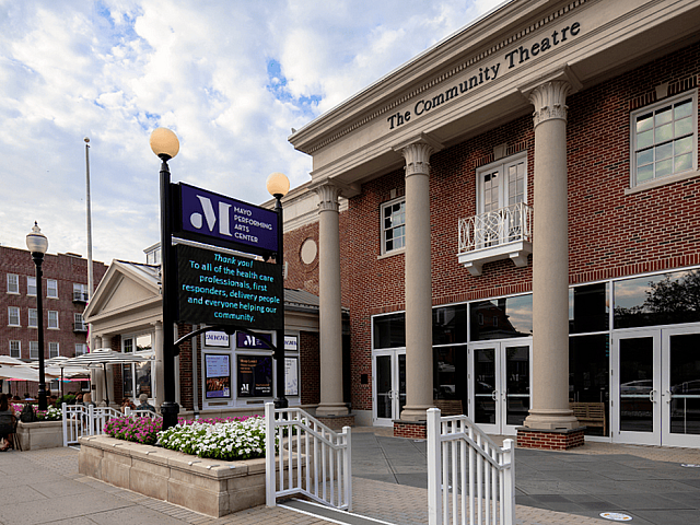 Charming community theatre with elegant columns and lively outdoor seating, perfect for cultural enthusiasts.
