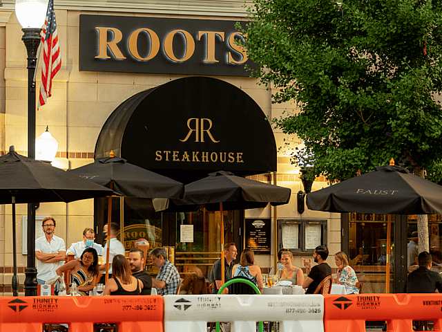 Inviting outdoor dining at a chic steakhouse, with patrons enjoying a lively atmosphere under elegant black umbrellas.