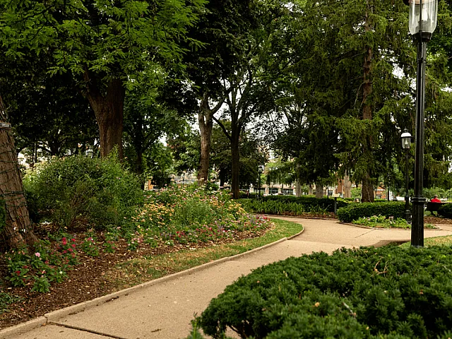 Charming park view featuring lush greenery, flower-lined pathways, and classic street lamps for a serene urban escape.