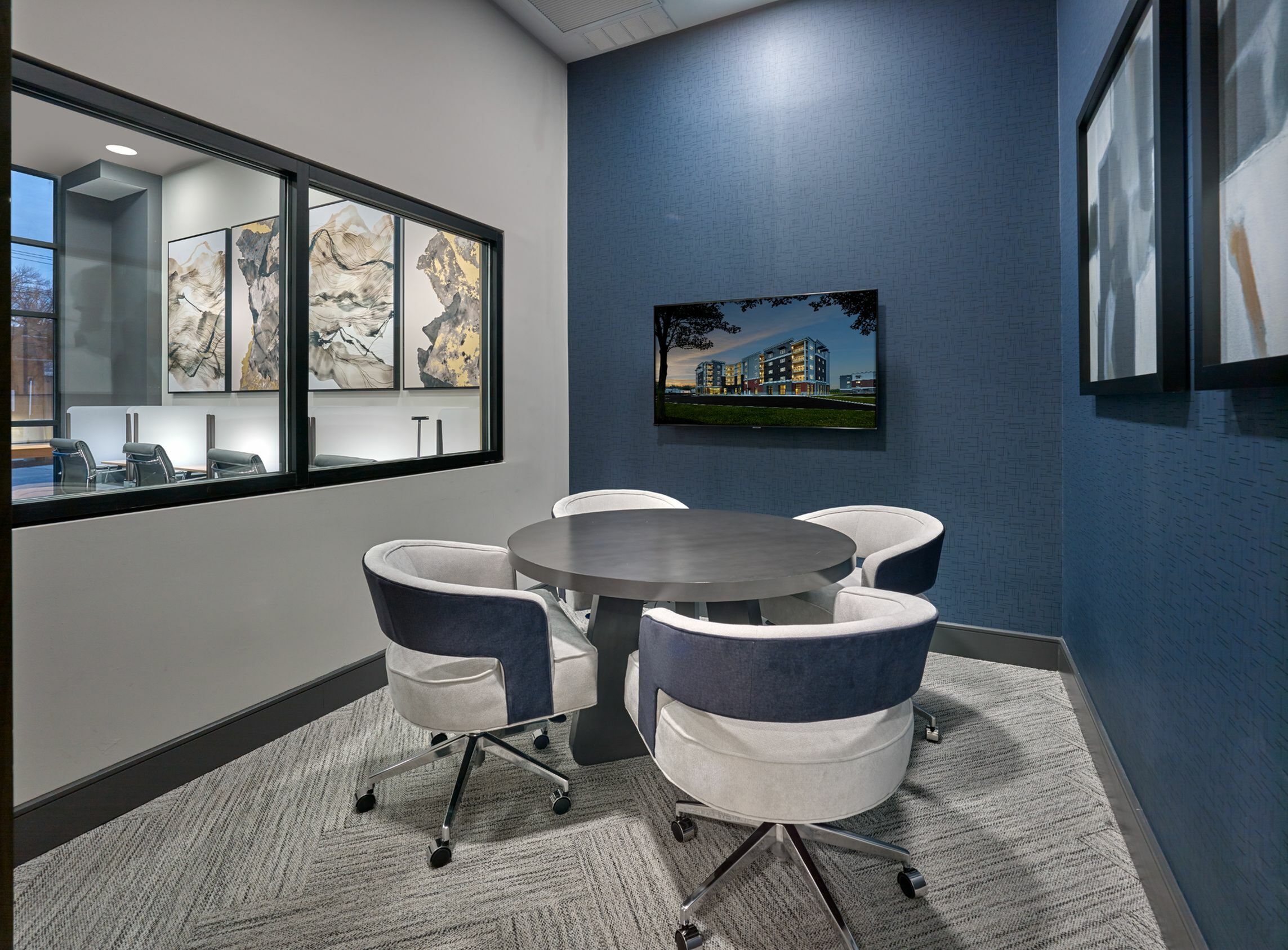 Modern meeting room with a stylish round table, elegant seating, and dynamic wall art, creating a sophisticated workspace.