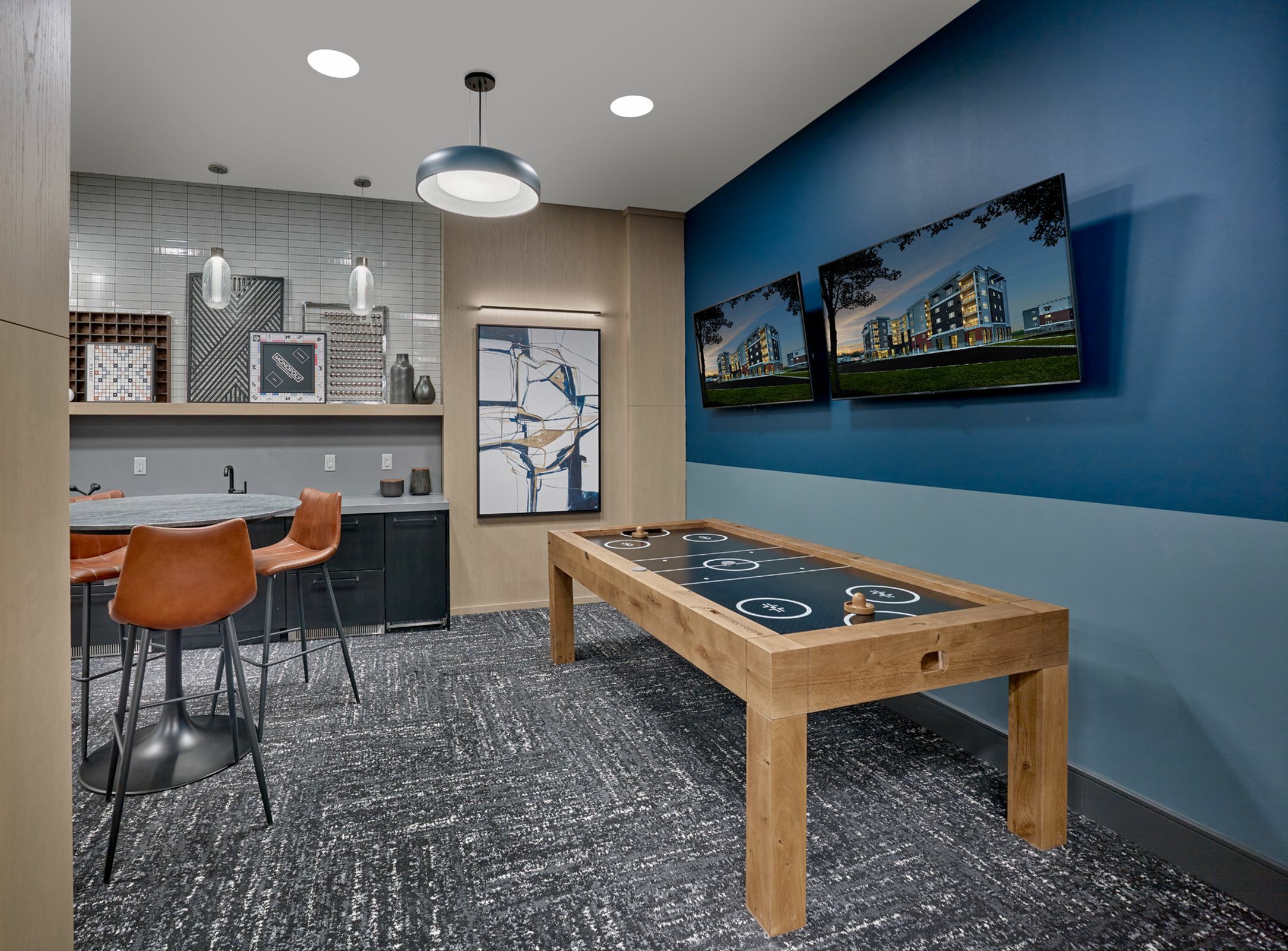 Chic entertainment space featuring a modern game table, stylish bar seating, and vibrant wall art, perfect for socializing.