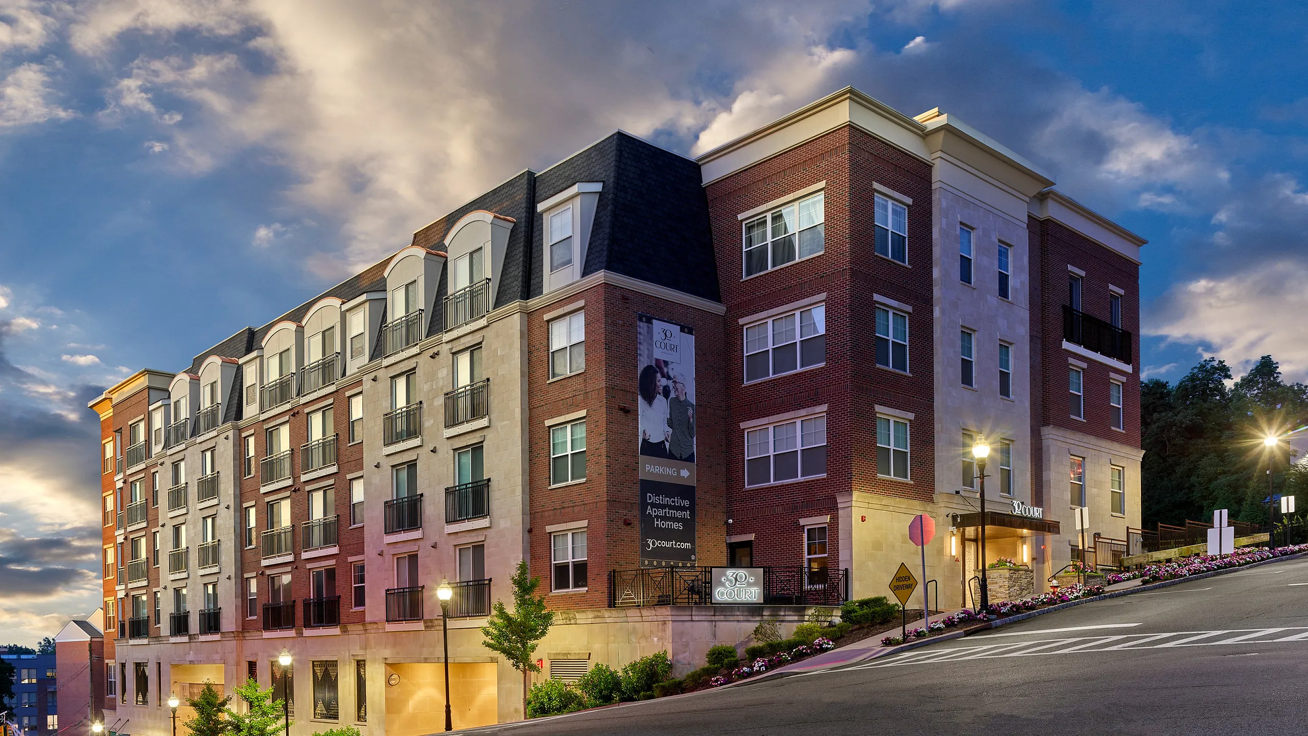Elegant multi-story apartment building under a dramatic sky, showcasing modern architecture and city living.