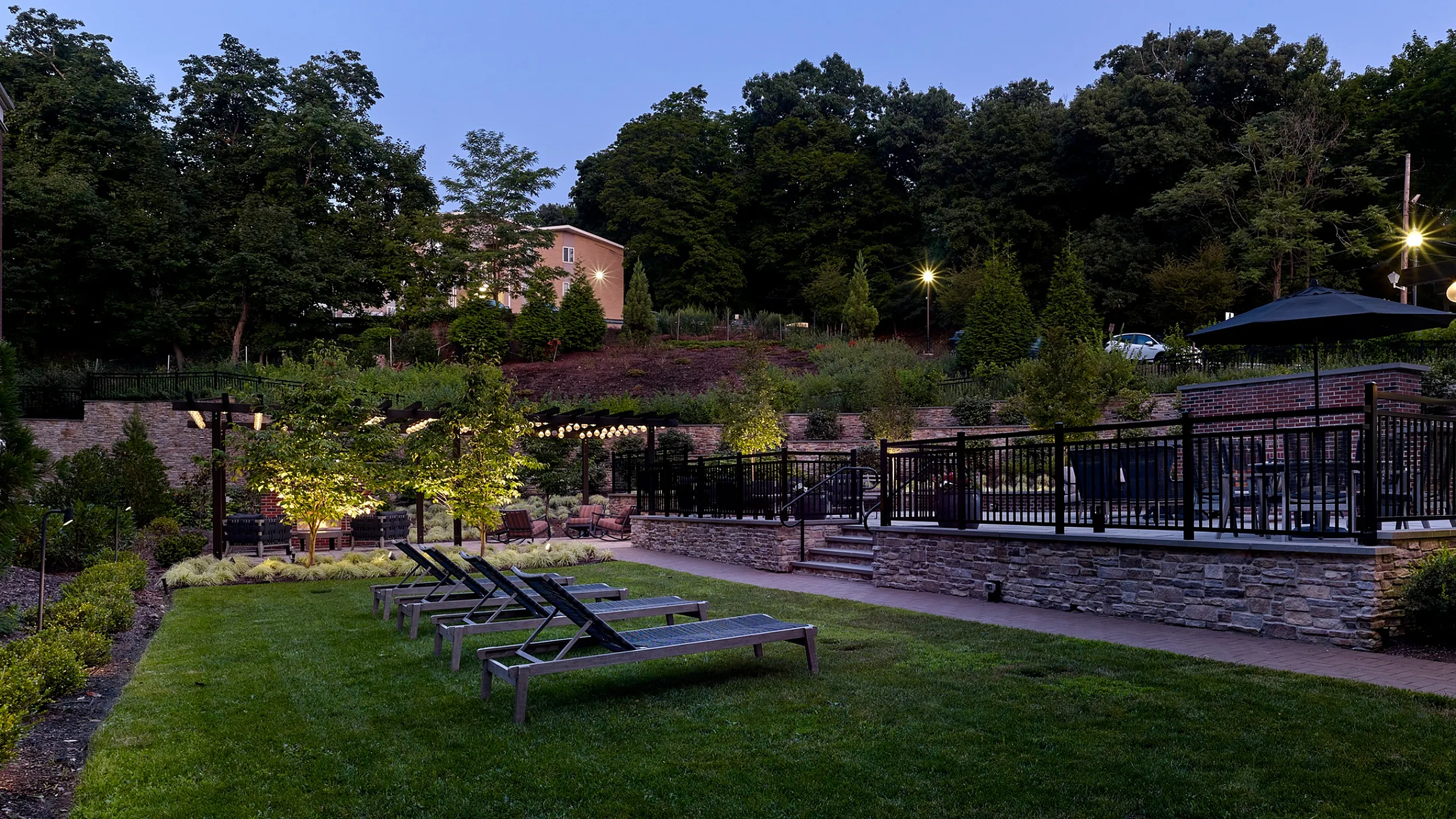 Charming garden area with lounge chairs, ambient lighting, and lush greenery inviting relaxation.