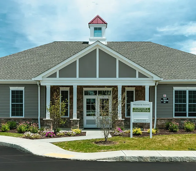 Charming clubhouse exterior with manicured landscaping and traditional architecture under a bright blue sky.