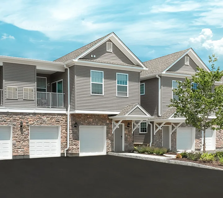 Elegant apartment complex featuring modern architecture, lush landscaping, and spacious balconies under a clear blue sky.