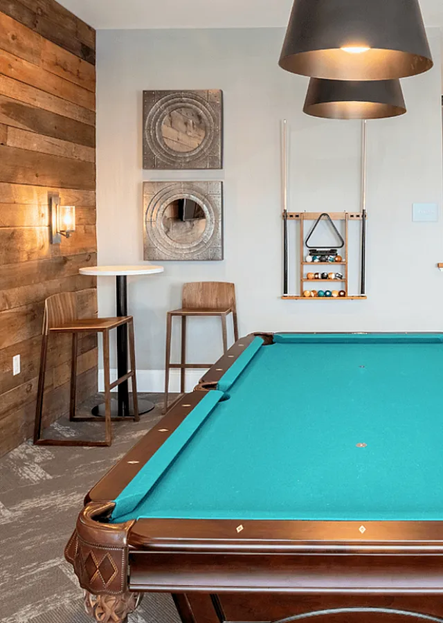 Chic entertainment room featuring a stylish pool table, rustic wood accent wall, and modern decor, perfect for relaxation and fun.