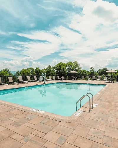 Inviting outdoor pool area with scenic views, surrounded by comfortable loungers and vibrant greenery, perfect for relaxation.