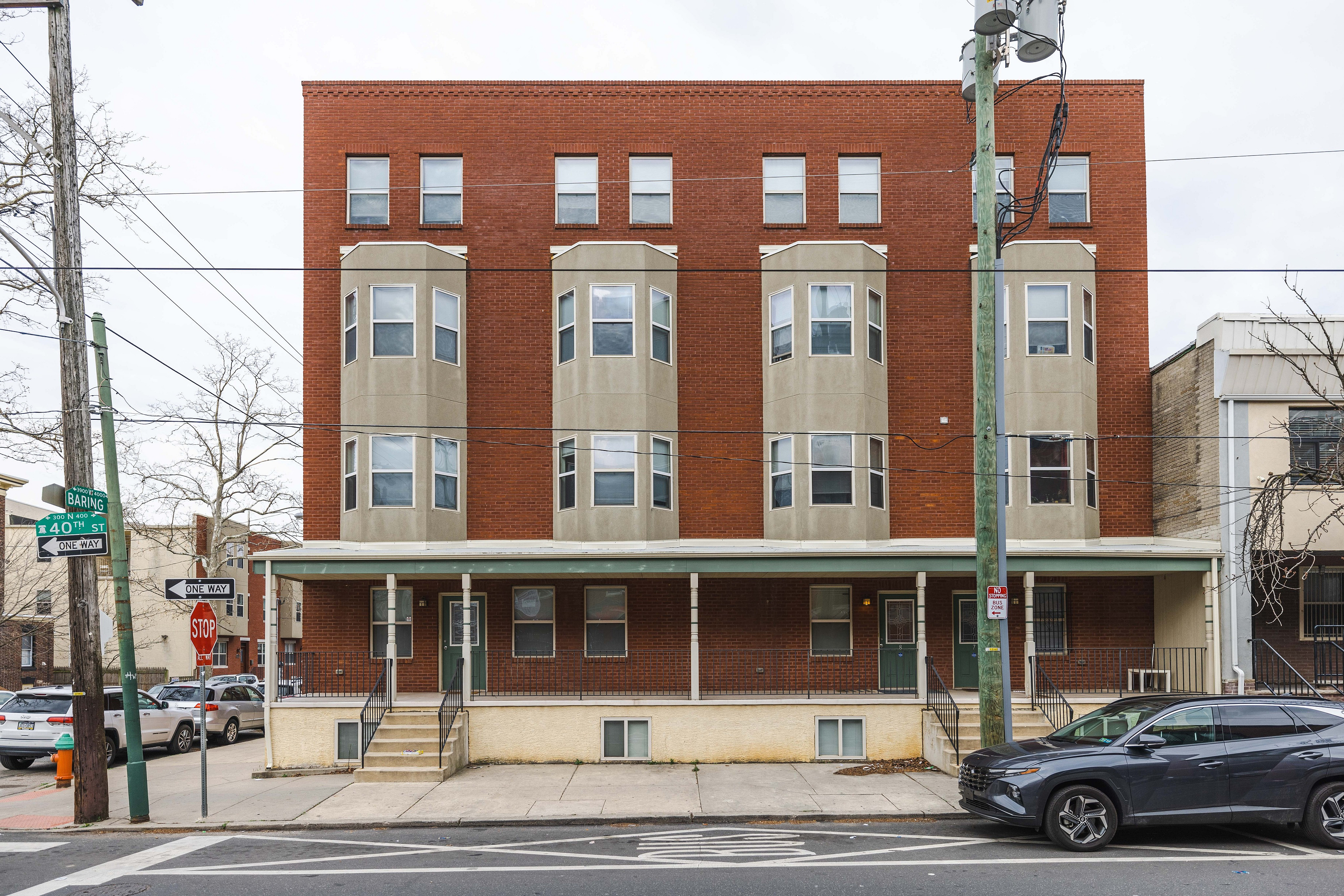 Charming multi-story brick building with bay windows on a vibrant city street corner, offering potential urban living spaces.