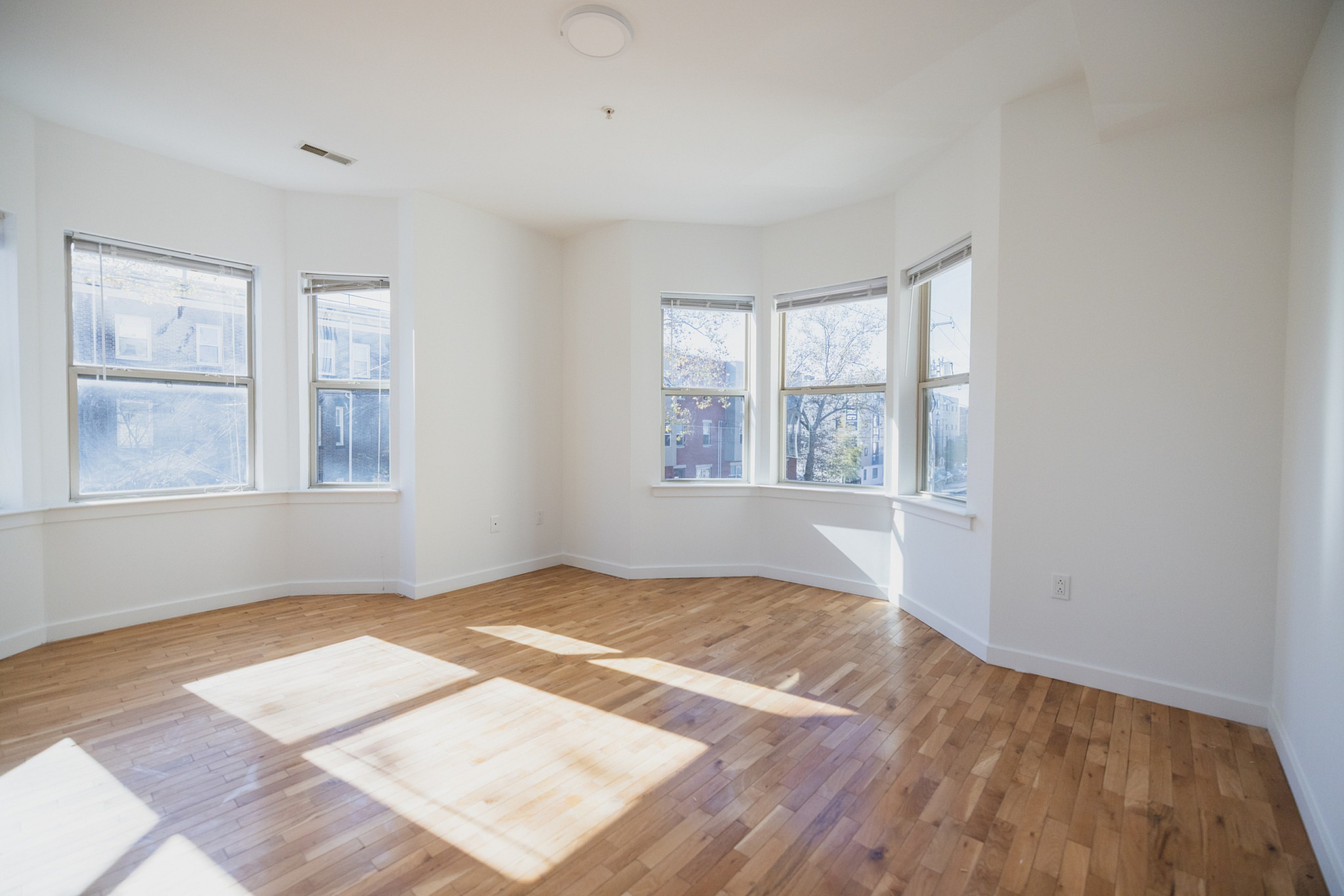 Bright and inviting room with large bay windows and gleaming hardwood floors, perfect for enjoying natural sunlight.