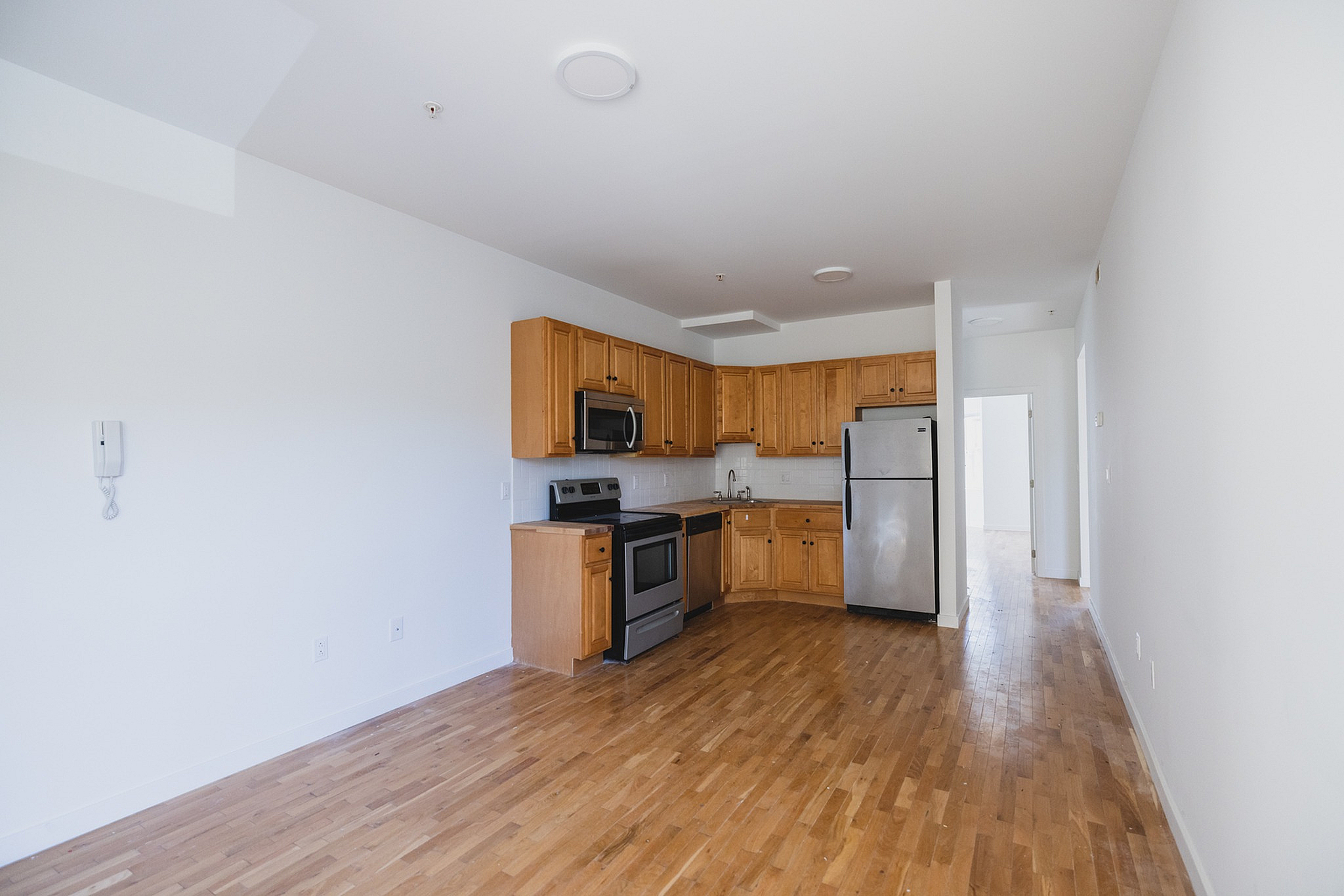 Chic open kitchen with modern stainless steel appliances, elegant wooden cabinetry, and sleek hardwood flooring.