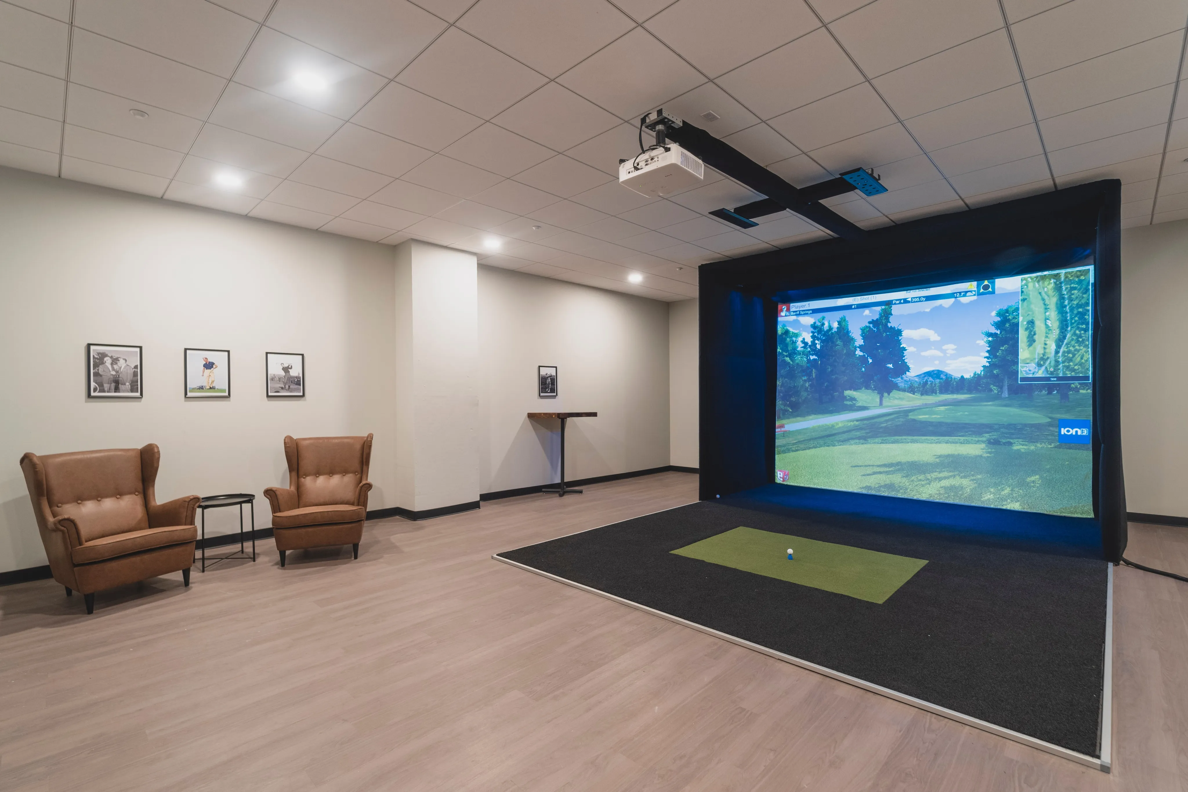 Modern recreational room featuring a high-tech golf simulator, comfortable leather seating, and stylish decor.