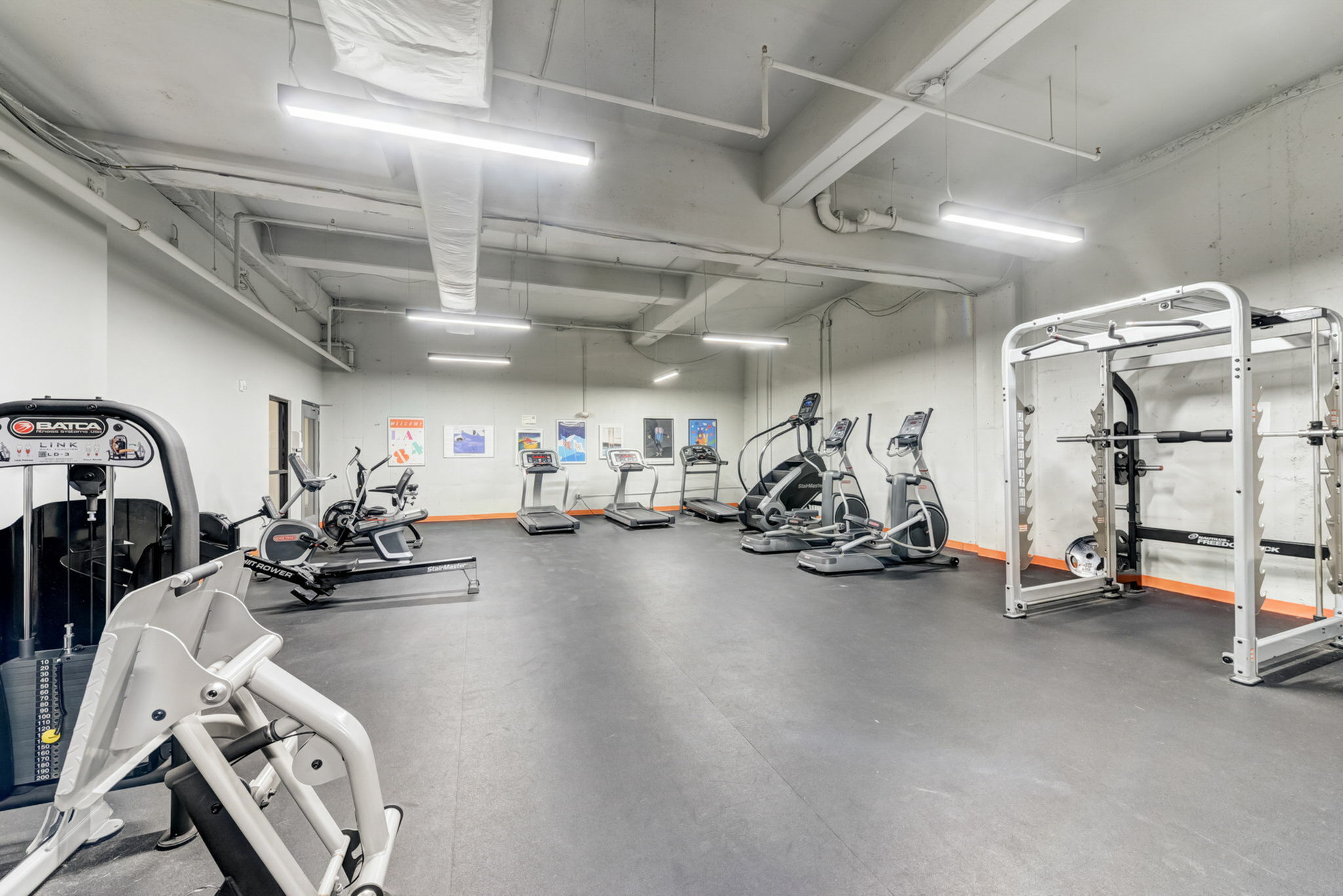 Spacious, modern gym filled with state-of-the-art equipment, featuring treadmills, elliptical machines, and a versatile weightlifting area.