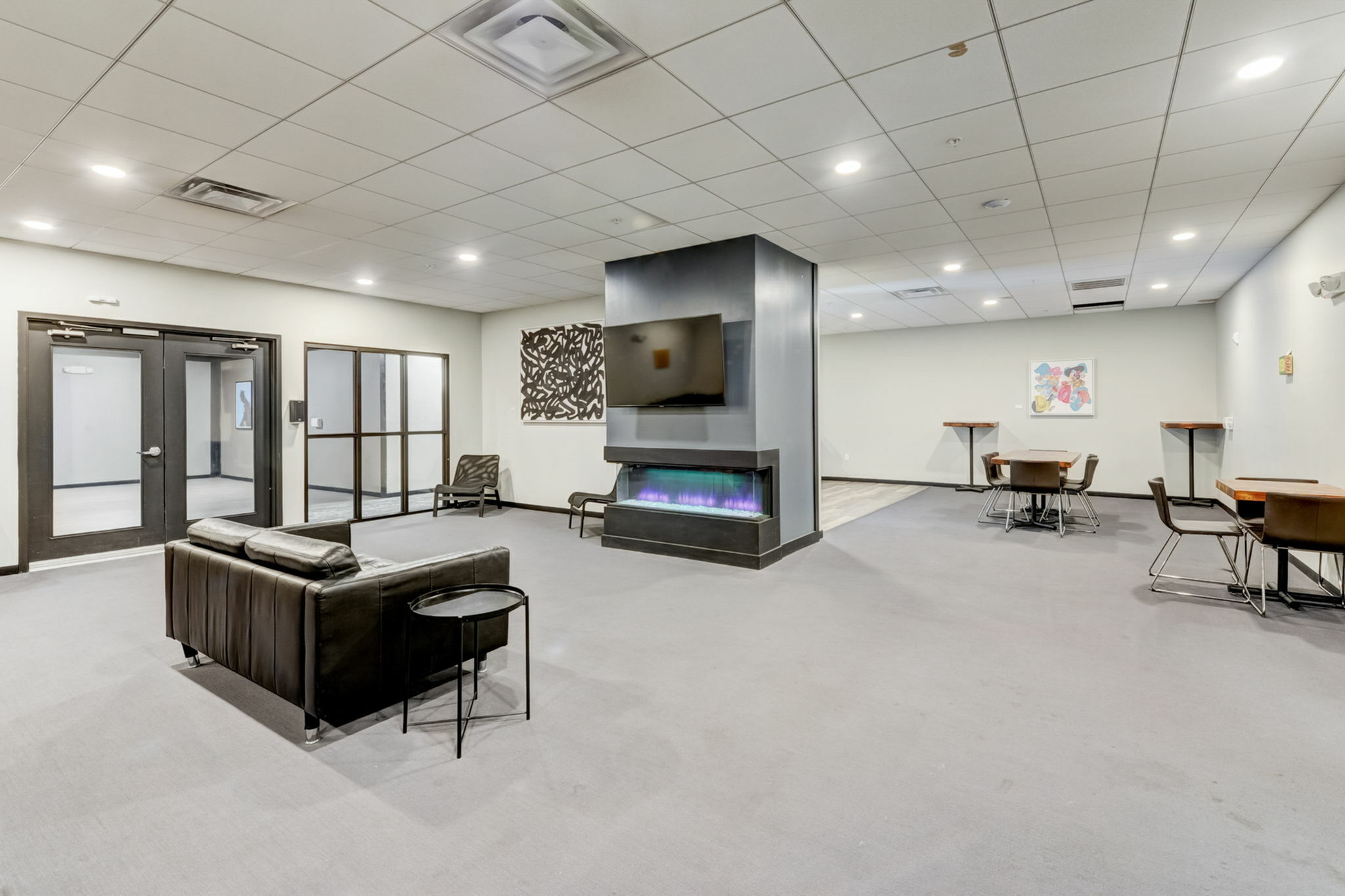 Modern lounge area with sleek black leather sofa, contemporary fireplace, and ambient lighting, perfect for relaxation and social gatherings.