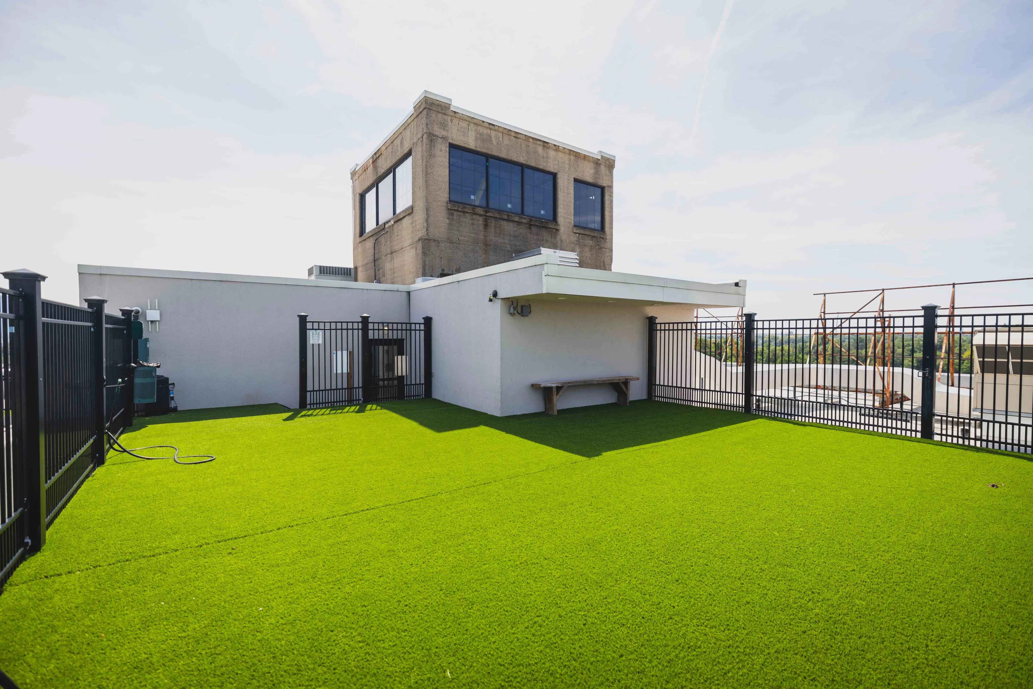 Spacious rooftop terrace featuring lush artificial grass, elegant fencing, and stunning city views.