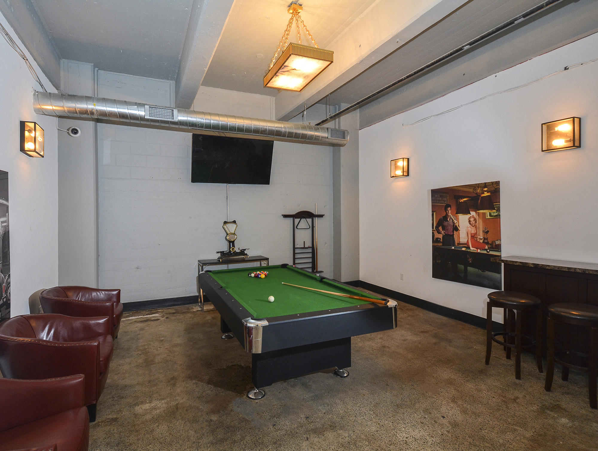 Chic game room featuring a sleek billiards table, cozy leather chairs, and ambient lighting for a relaxing atmosphere.