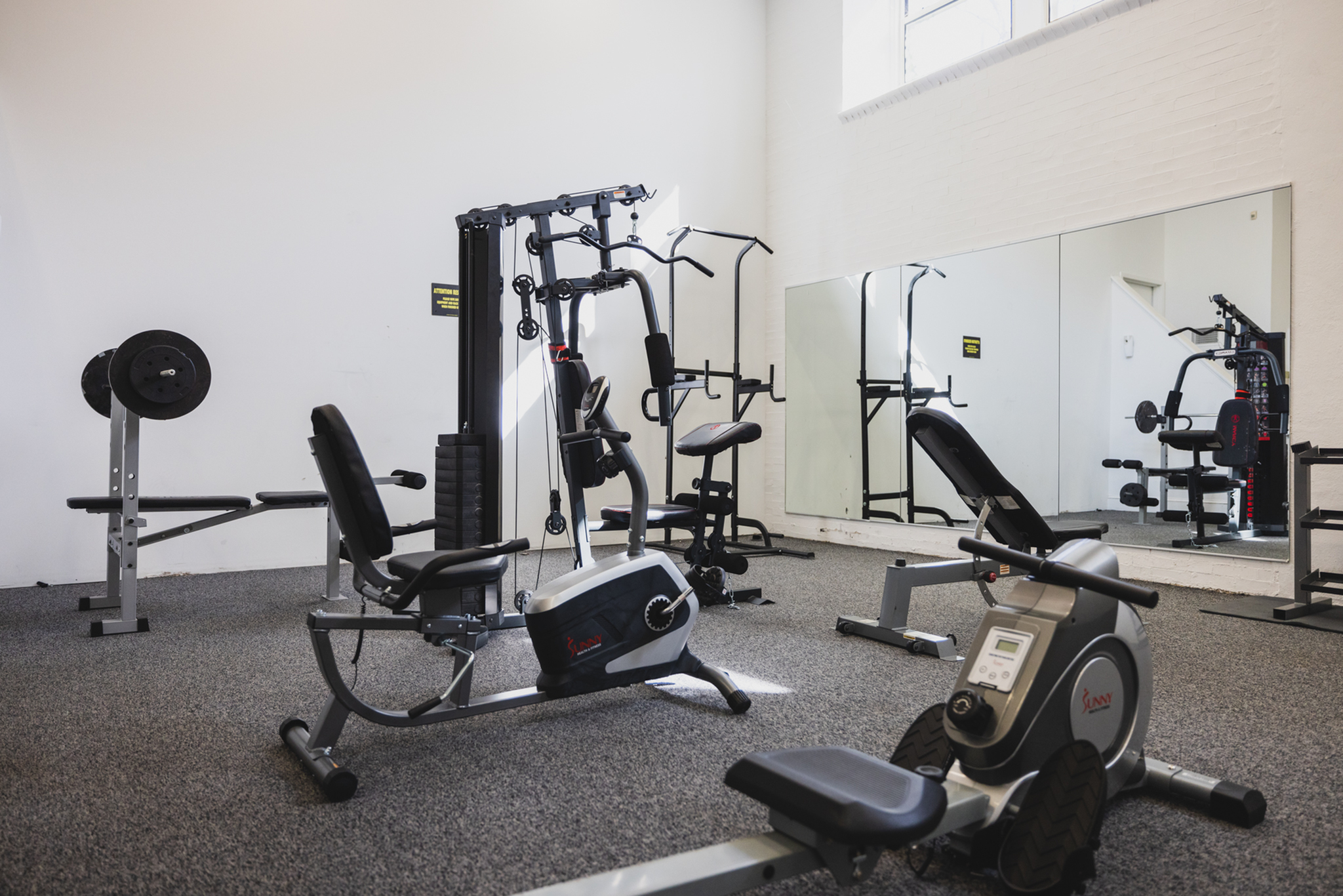 Bright and modern fitness center with state-of-the-art exercise equipment, including rowing machine and weight benches, perfect for active living.