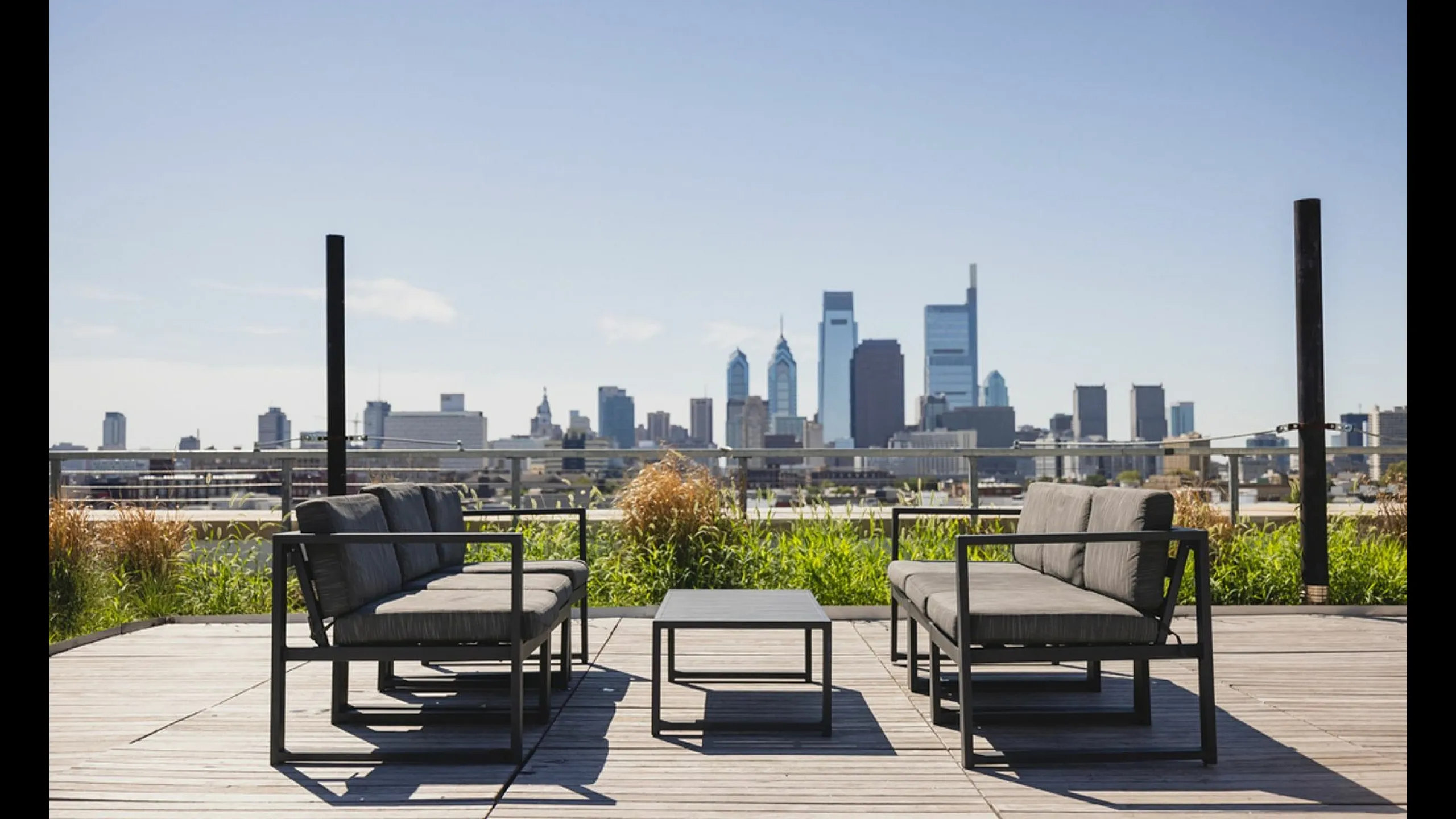 Chic rooftop patio with contemporary seating and panoramic city skyline view.