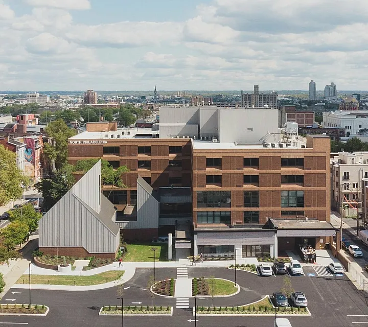 Aerial view of a modern apartment complex with spacious parking and urban landscape, located in a vibrant city district.