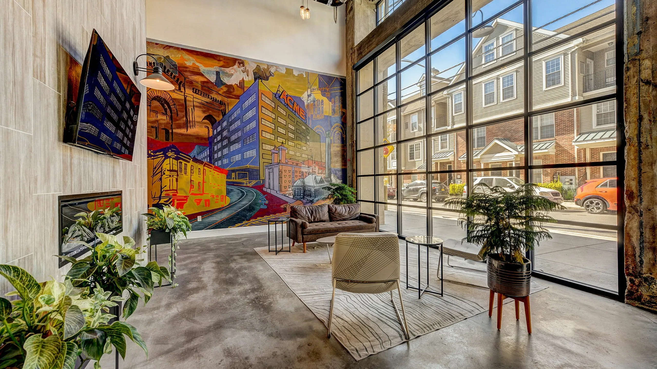 Modern lobby at Storehouse Lofts with vibrant mural, large windows, and cozy seating area.