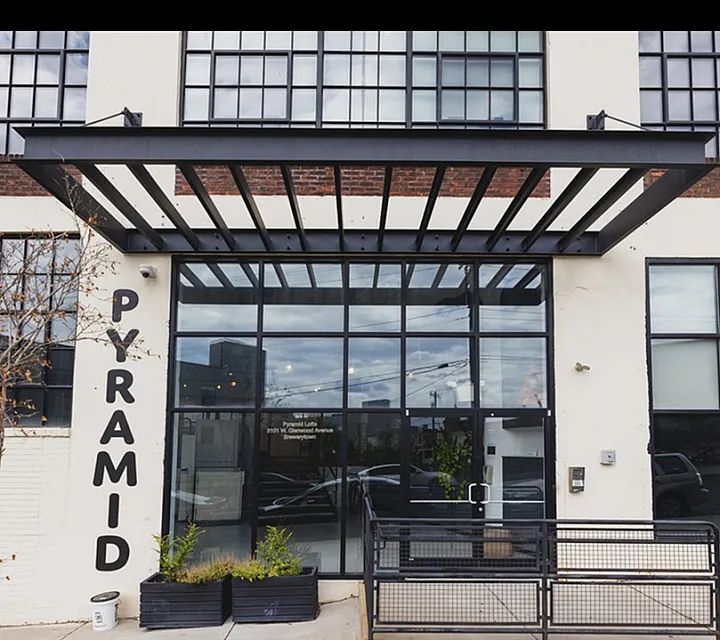 Modern industrial-style entrance of Pyramid Lofts featuring expansive windows and sleek, contemporary design elements.