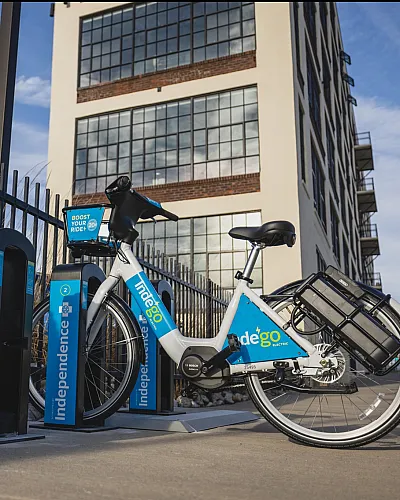 Urban bike-sharing station featuring sleek electric bicycles against a backdrop of a stylish modern building.