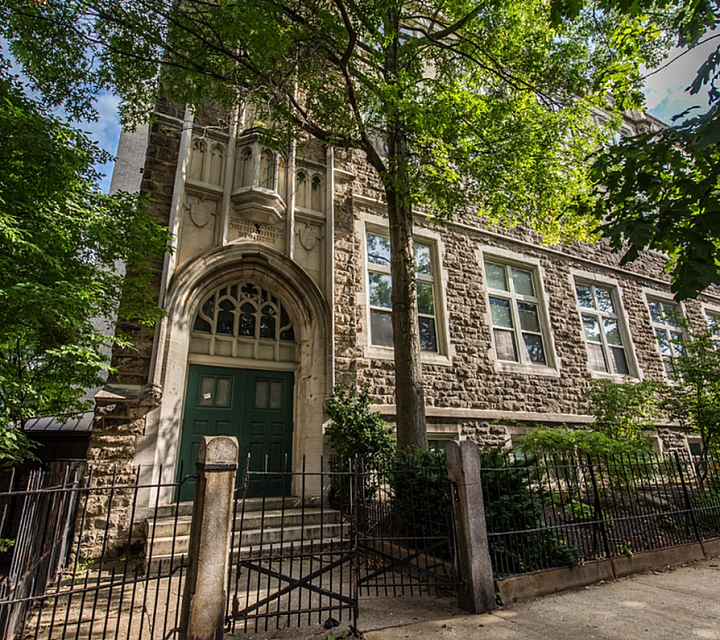 Vestry's stone building is nestled among lush green trees, featuring elegant architecture and inviting double doors.