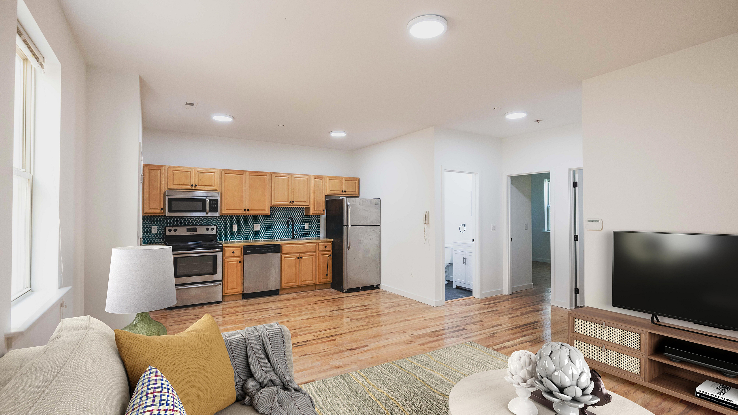 Modern open-concept living space featuring a sleek kitchen with stainless steel appliances, warm wooden cabinetry, and a chic living area with hardwood floors.
