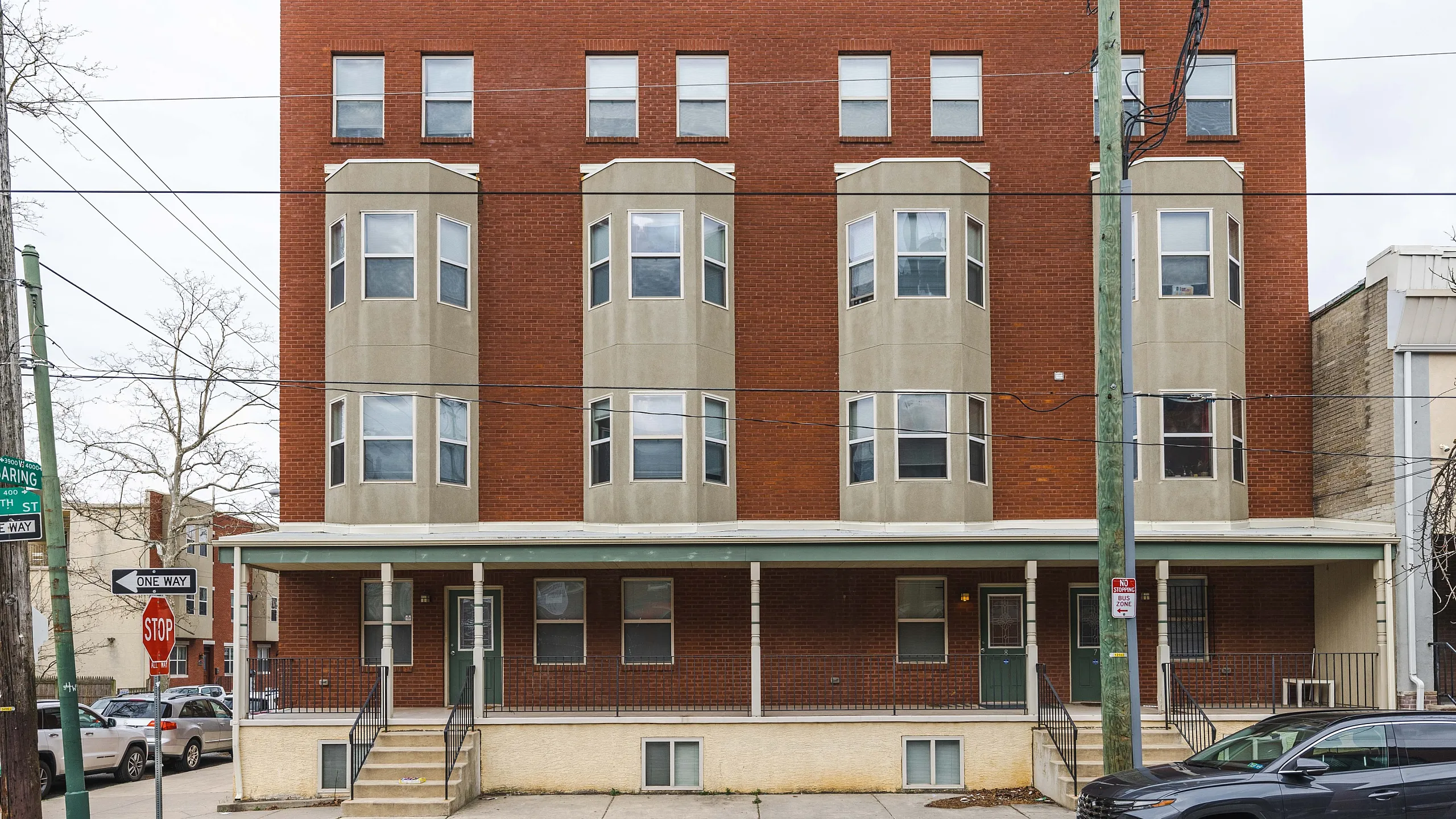 Charming red-brick apartment building with modern bay windows on a quiet urban street corner.