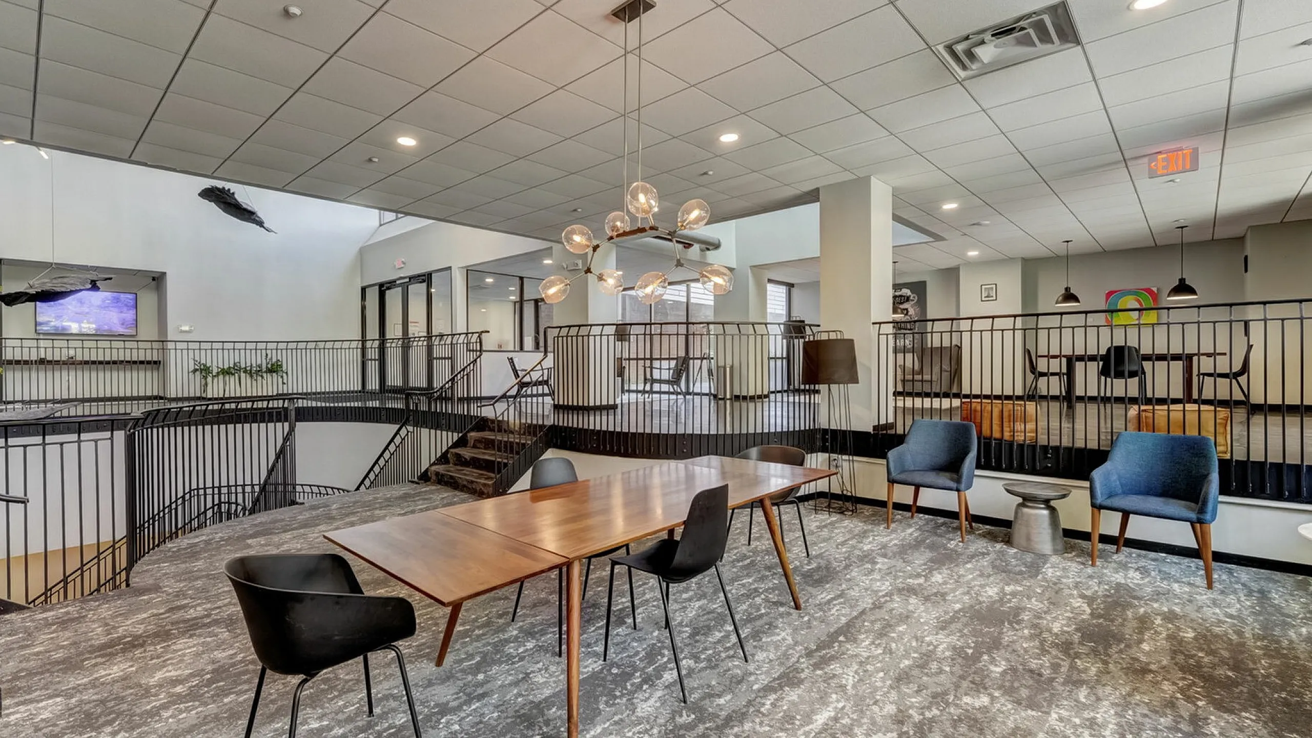 Chic communal area with a modern design featuring stylish seating, a large wooden table, and elegant lighting, perfect for gatherings or meetings.