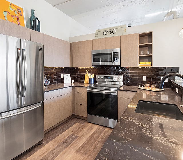 Modern kitchen with sleek appliances, elegant dark countertops, and stylish lighting, creating a sophisticated cooking space.