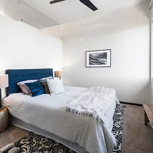 Elegant bedroom with a plush bed, stylish blue headboard, and cozy lighting perfect for relaxation.