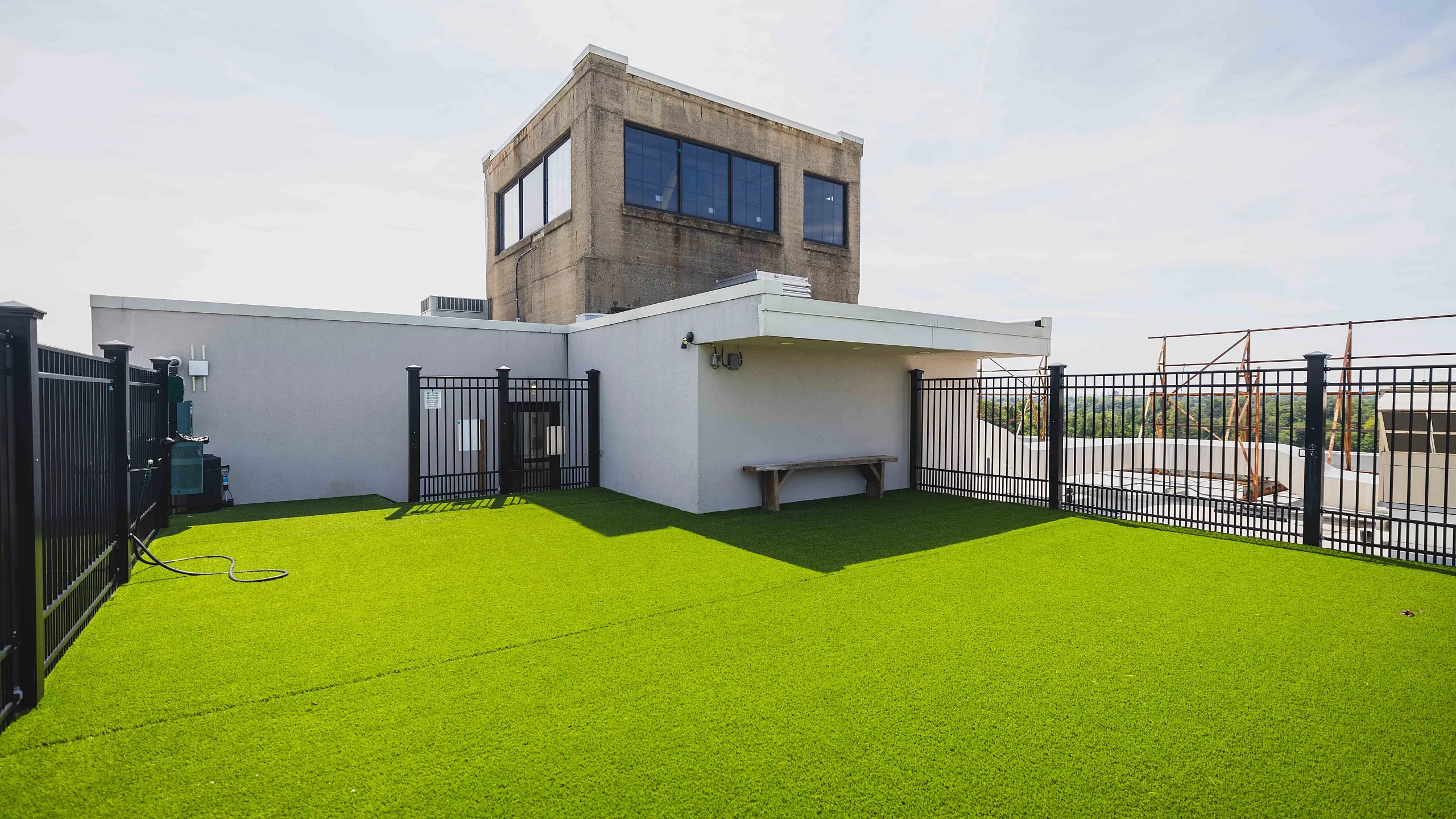 Spacious rooftop terrace with fresh green artificial turf, modern fencing, and a stunning cityscape view.