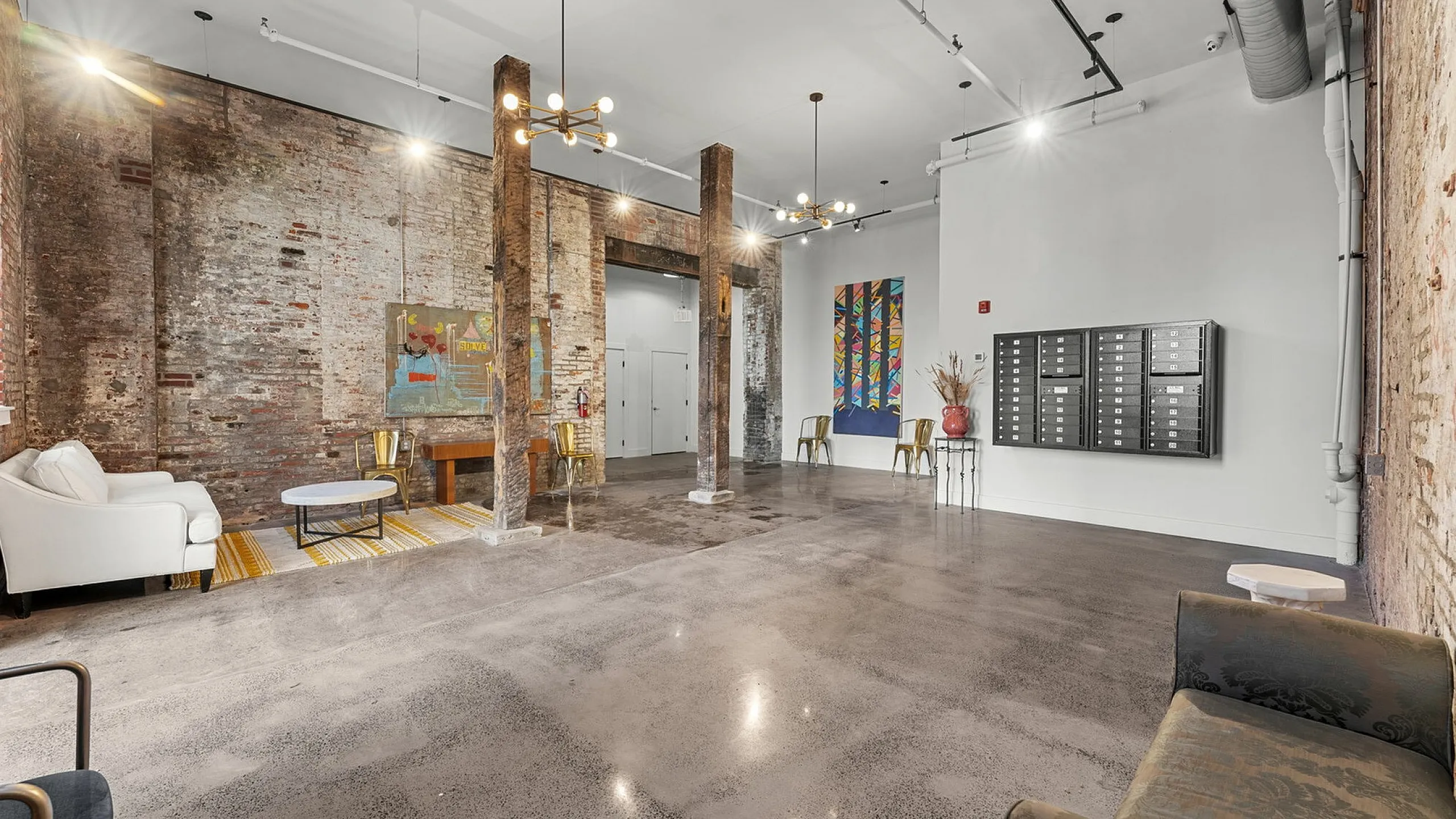 Chic industrial-style apartment lobby with exposed brick walls, polished concrete floors, and modern lighting fixtures.