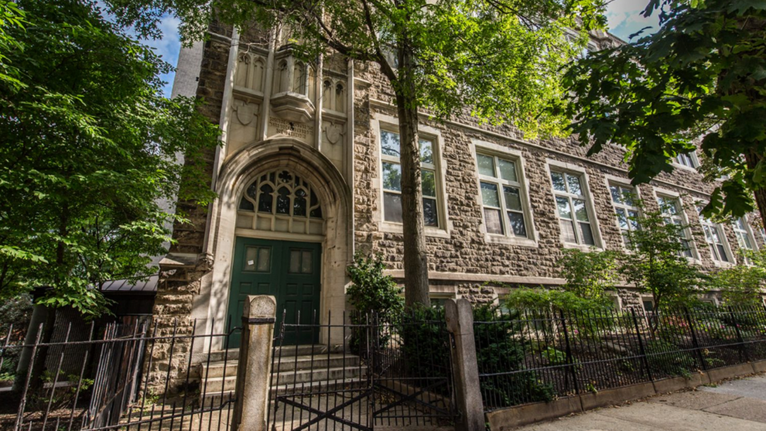 Charming historic building with stunning stone architecture surrounded by lush greenery and trees.