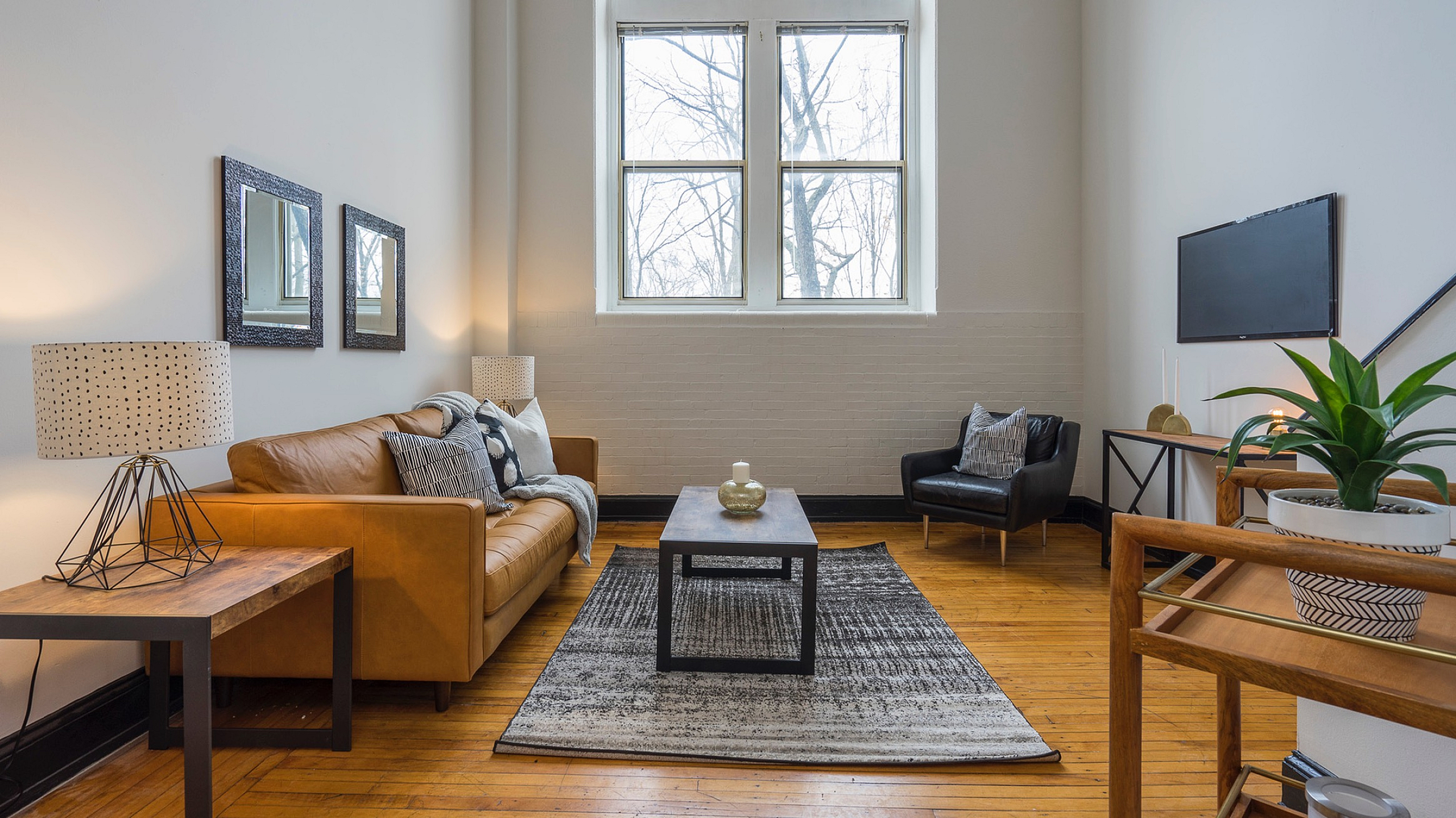 Inviting living room with a high ceiling, featuring a cozy leather sofa, modern decor, and large windows filling the space with natural light.