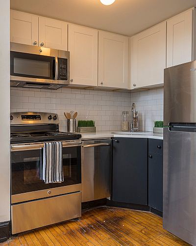 Chic apartment kitchen with modern stainless steel appliances, sleek cabinetry, and a sophisticated wooden cart for added elegance.