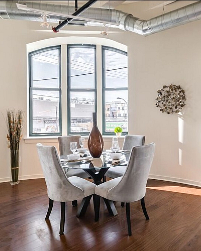 Bright dining area with elegant decor, featuring a round glass table set for four under large arched windows.