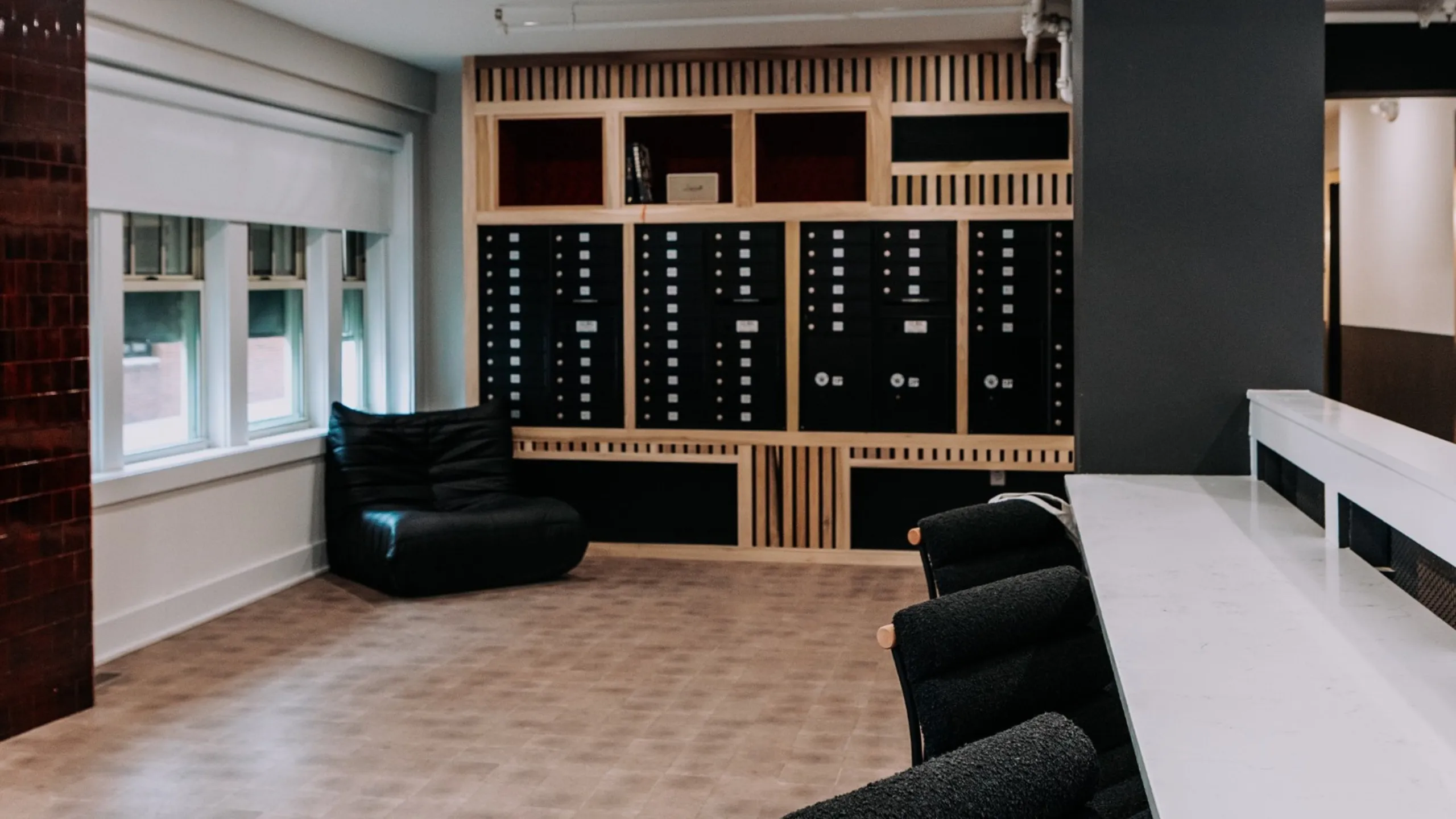 Modern apartment lobby with stylish mailboxes, cozy seating area, and a sleek countertop for a welcoming atmosphere.
