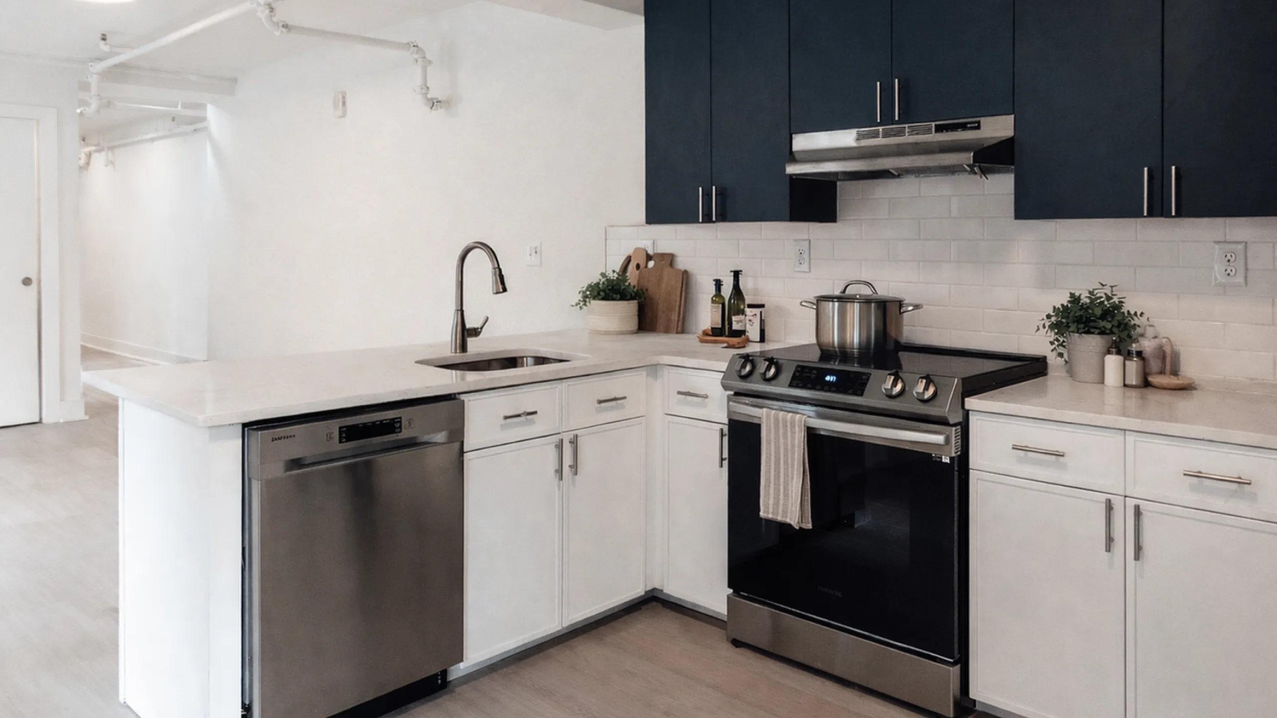 Modern kitchen with sleek stainless steel appliances, elegant dark cabinetry, and a stylish white tile backsplash.