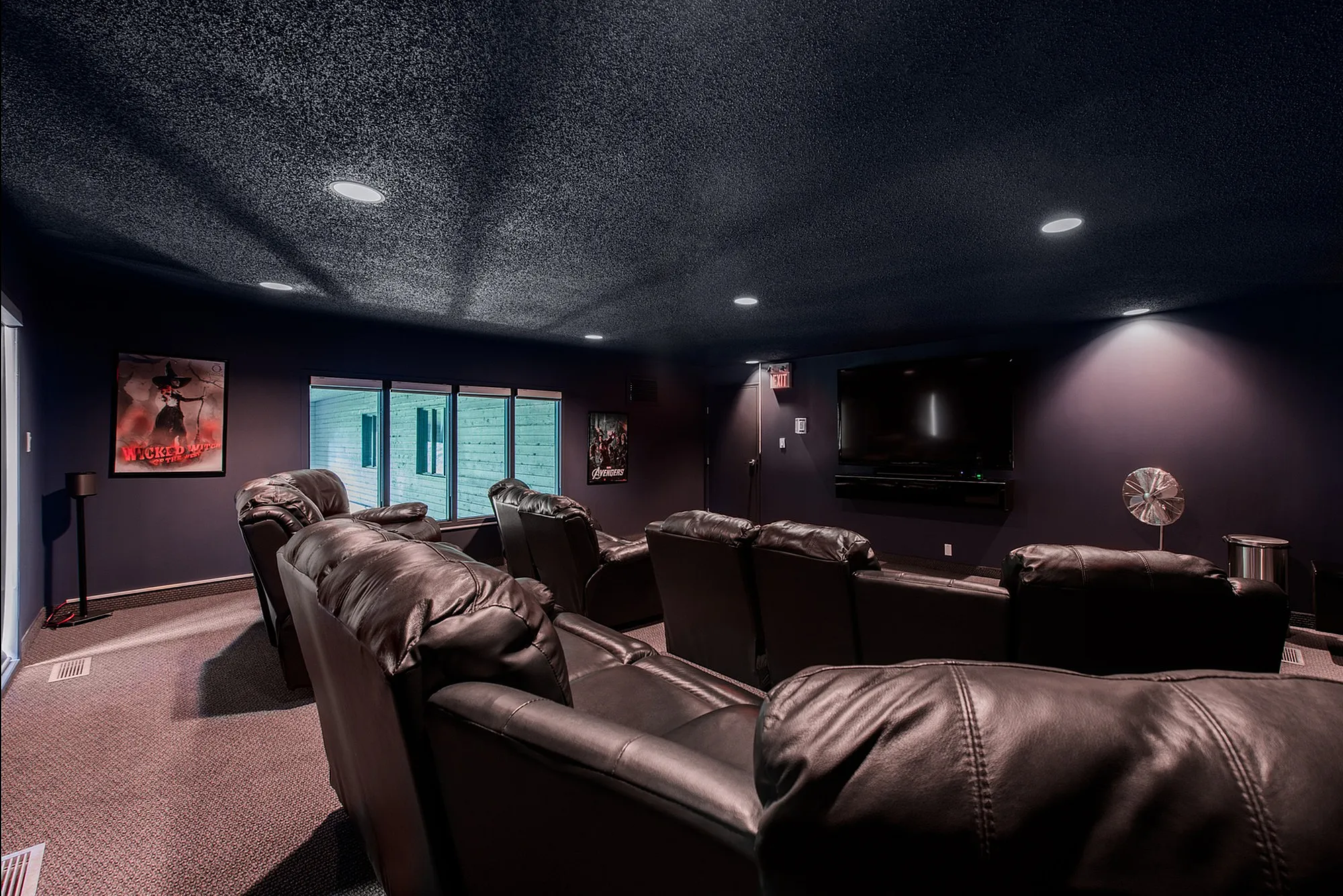 Luxurious home theater room featuring plush leather reclining seats, ambient lighting, and a large flat-screen TV for an ultimate entertainment experience.