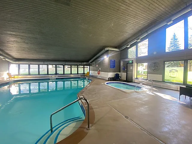 Bright indoor swimming pool area with large windows, tranquil ambiance, and inviting water, perfect for relaxation and recreation.